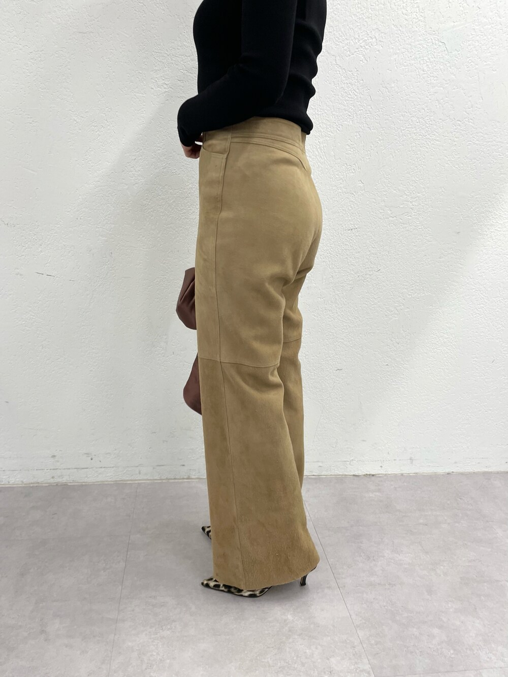 イエロー系のパンプス、イエロー系のパンツ、ブラウン系のハンドバッグを着用したレディースの冬コーディネートの5枚目の写真