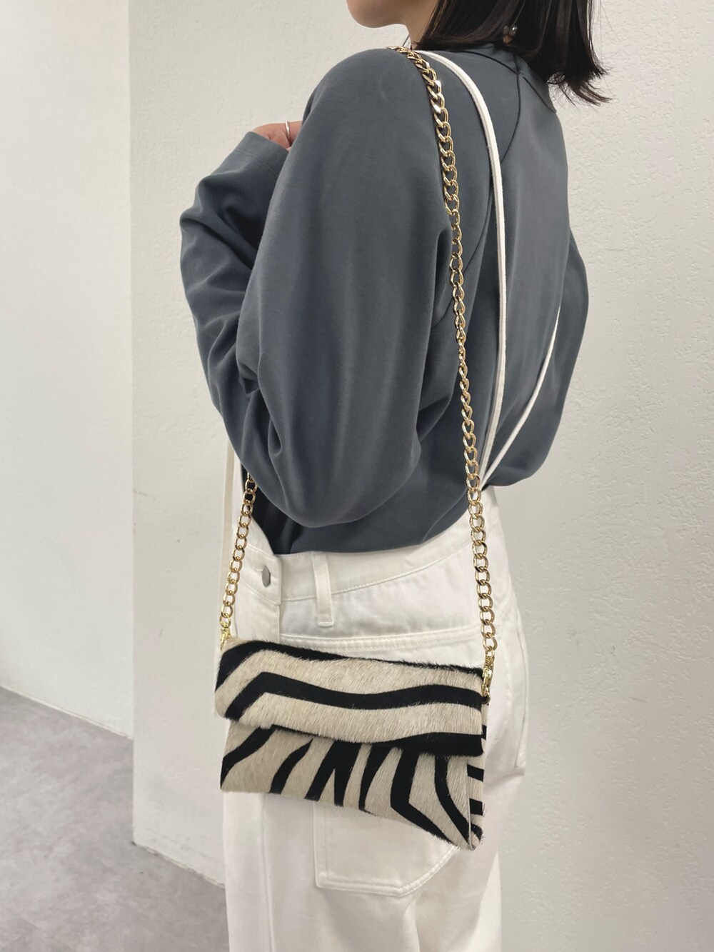 ブラック系のショルダーバッグ、ゴールド系のサンダル、ホワイト系のサロペット/オーバーオールを着用したレディースの冬コーディネートの5枚目の写真