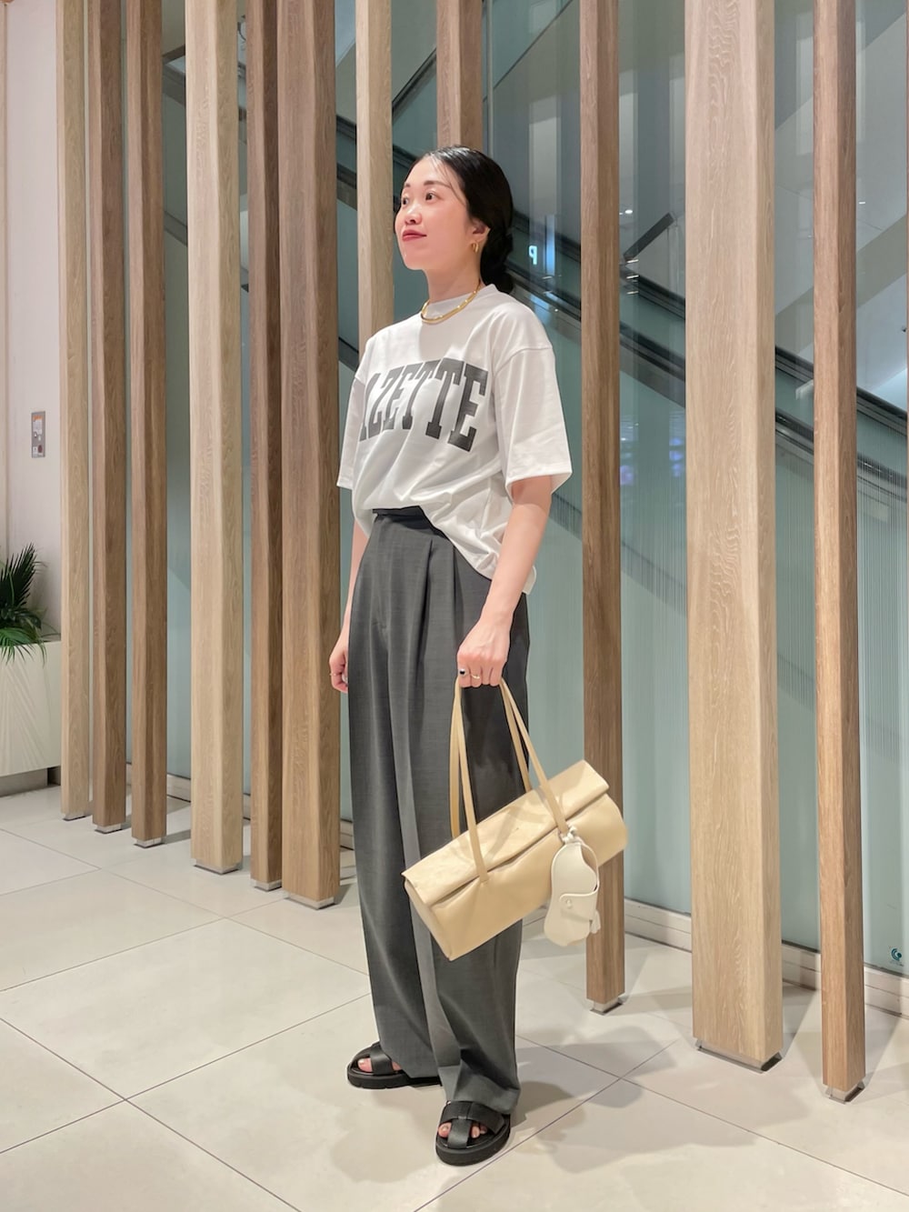 グレー系のスラックス、ベージュ系のハンドバッグ、ブラック系のサンダルを着用したレディースの春コーディネートの6枚目の写真