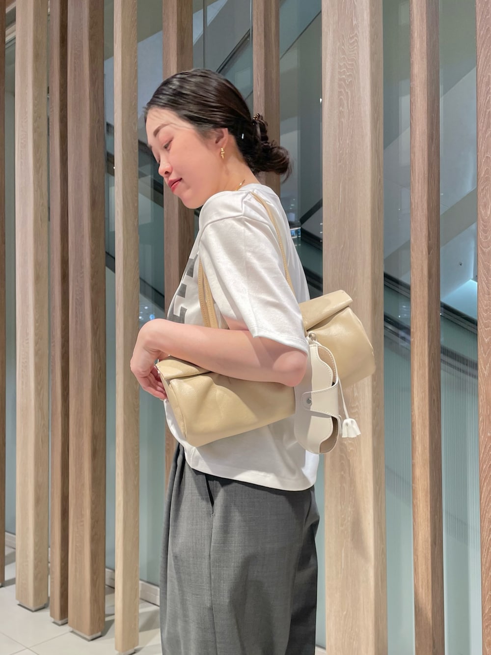 グレー系のスラックス、ベージュ系のハンドバッグ、ブラック系のサンダルを着用したレディースの春コーディネートの8枚目の写真