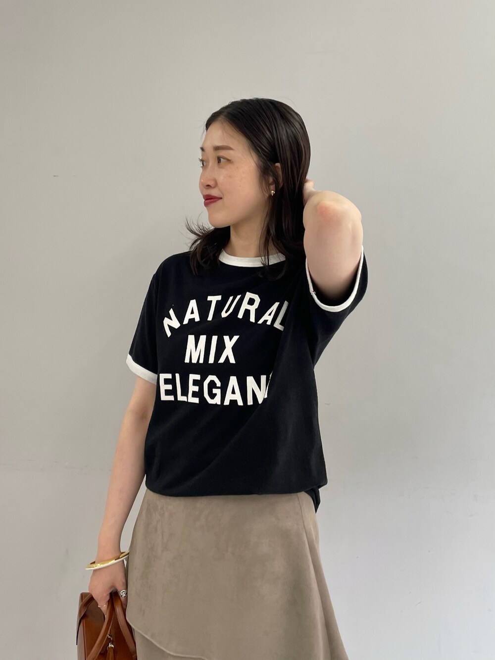 ブラック系のTシャツ/カットソー、ベージュ系のスカート、ゴールド系のブレスレットを着用したレディースの夏コーディネートの3枚目の写真