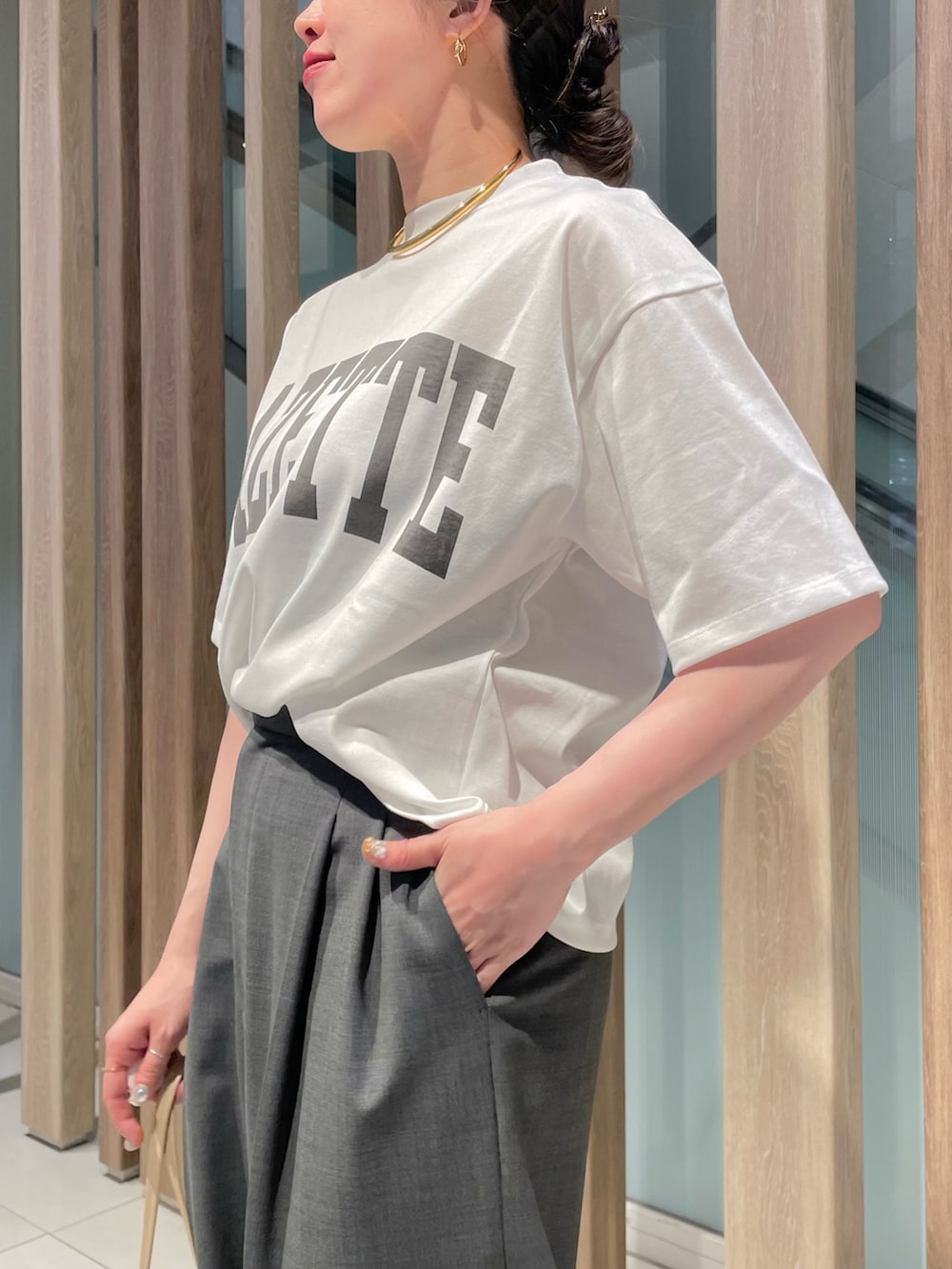 グレー系のスラックス、ベージュ系のハンドバッグ、ブラック系のサンダルを着用したレディースの春コーディネートの7枚目の写真