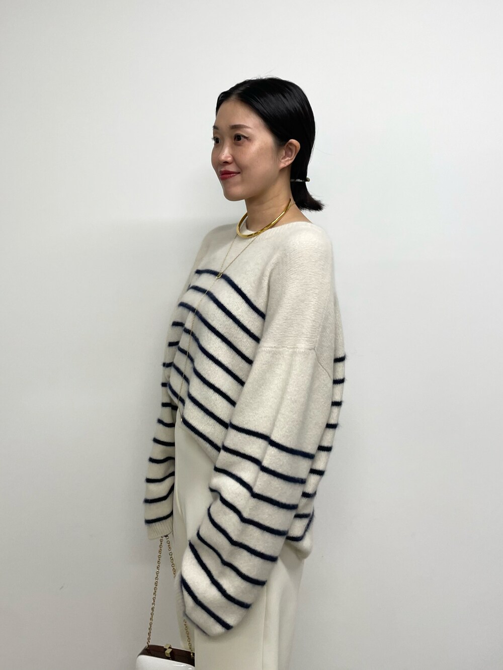 ホワイト系のスラックス、ブラウン系のブーツ、ブルー系のニット/セーターを着用したレディースの秋コーディネートの3枚目の写真