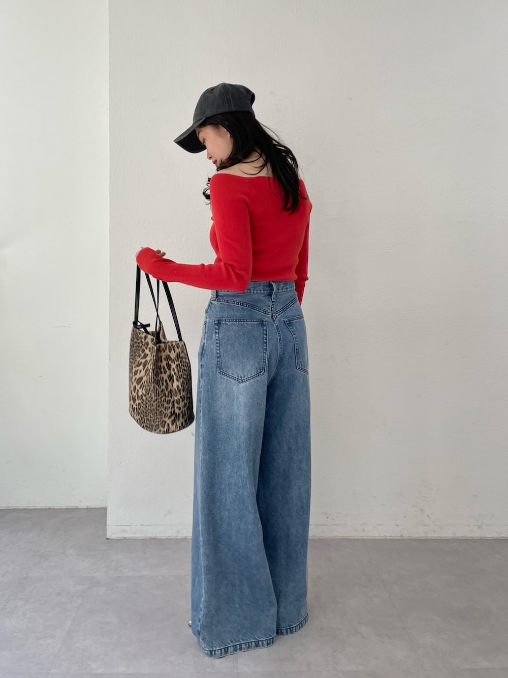 ブルー系のデニムパンツ、ゴールド系のパンプス、レッド系のニット/セーターを着用したレディースの春コーディネートの2枚目の写真