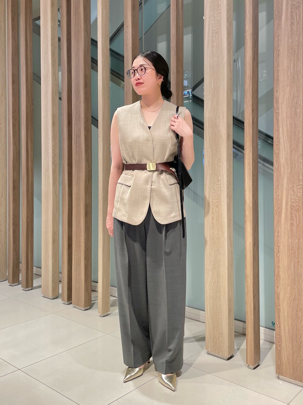 ベージュ系のベスト、ブラック系のショルダーバッグ、グレー系のスラックスを着用したレディースの春コーディネートの6枚目の写真