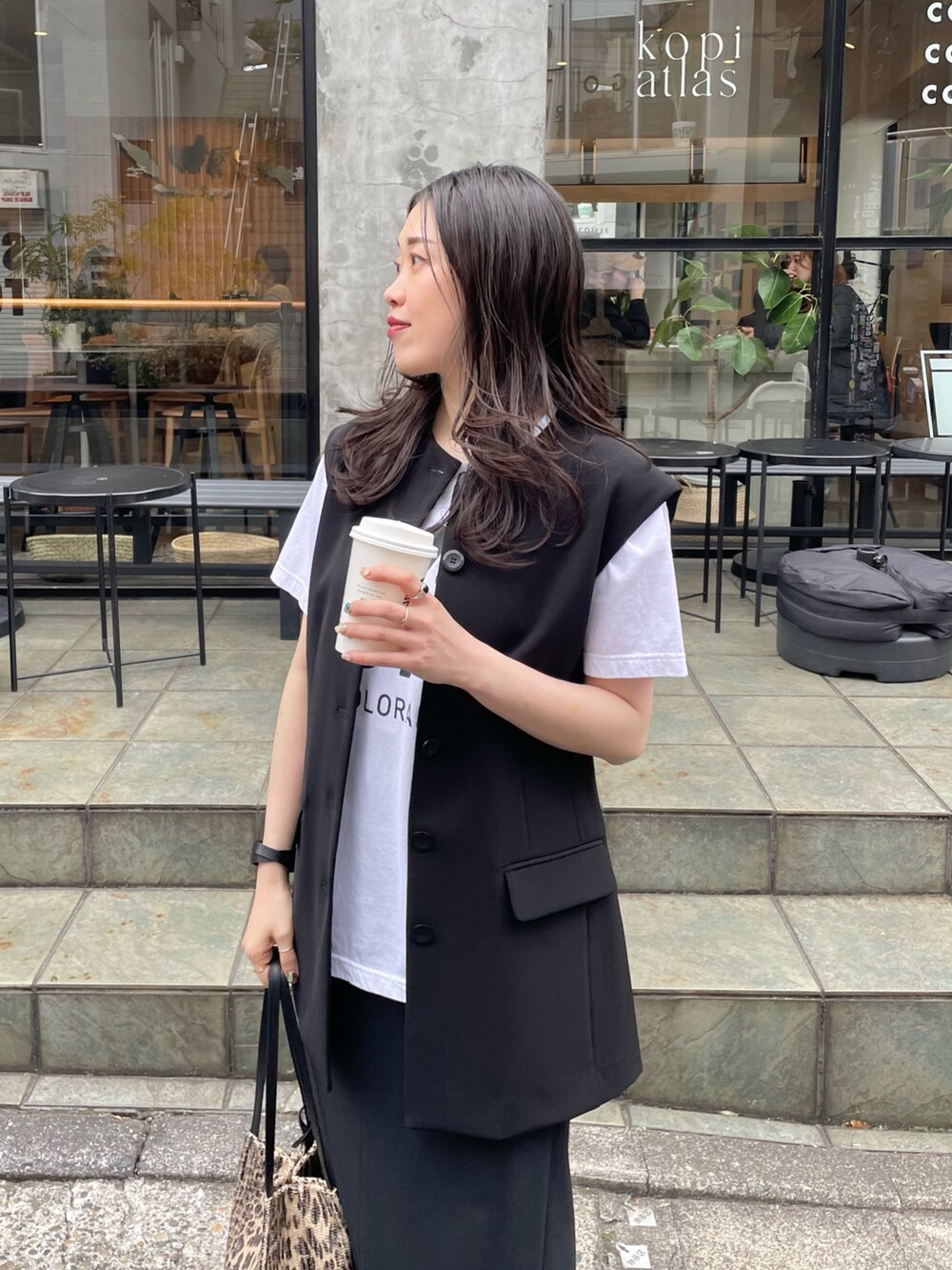 ブラック系のスカート、ブラック系のベスト、ブラウン系のトートバッグを着用したレディースの春コーディネートの3枚目の写真