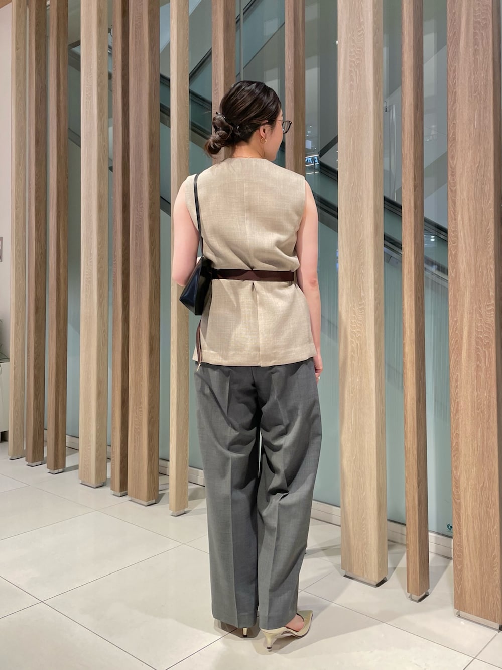 ベージュ系のベスト、ブラック系のショルダーバッグ、グレー系のスラックスを着用したレディースの春コーディネートの7枚目の写真