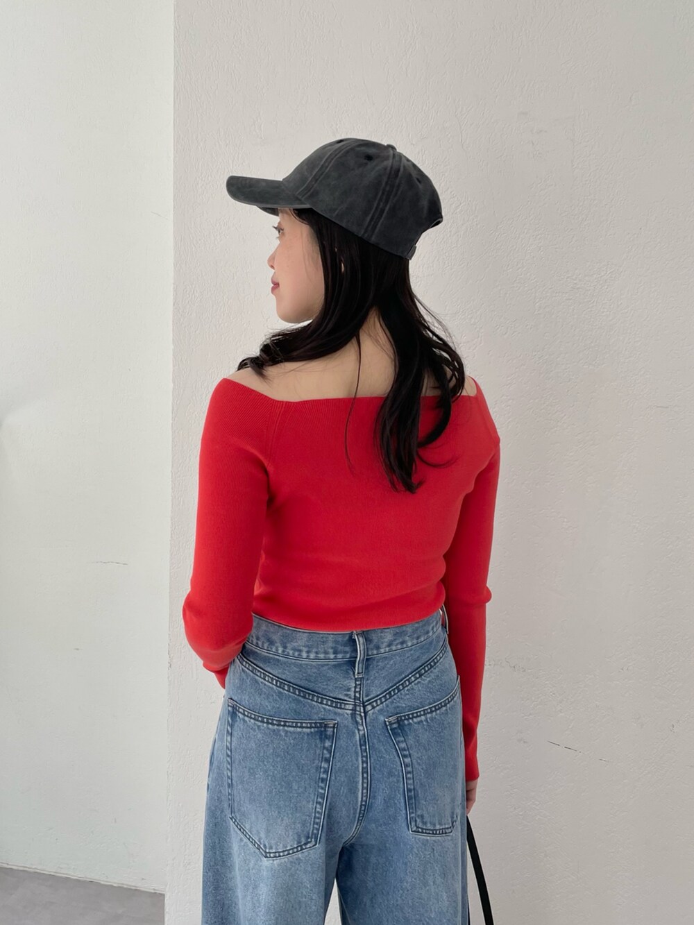 ブルー系のデニムパンツ、ゴールド系のパンプス、レッド系のニット/セーターを着用したレディースの春コーディネートの4枚目の写真