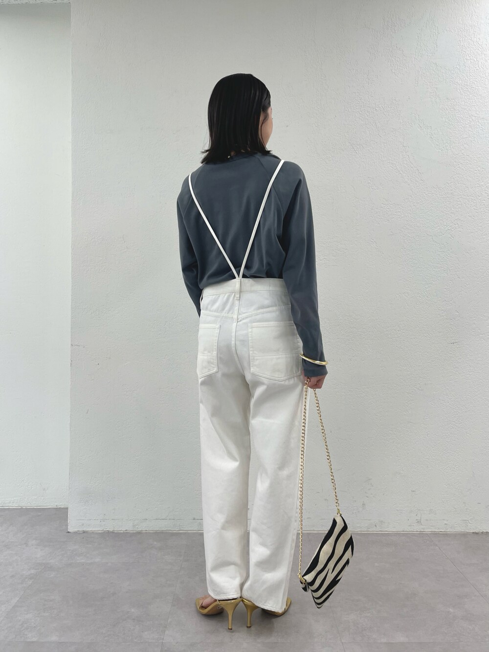 ブラック系のショルダーバッグ、ゴールド系のサンダル、ホワイト系のサロペット/オーバーオールを着用したレディースの冬コーディネートの2枚目の写真