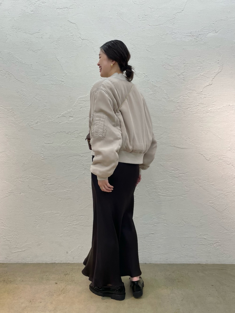 ブラック系のローファー、ブラウン系のスカート、ブラウン系のショルダーバッグを着用したレディースの夏コーディネートの2枚目の写真