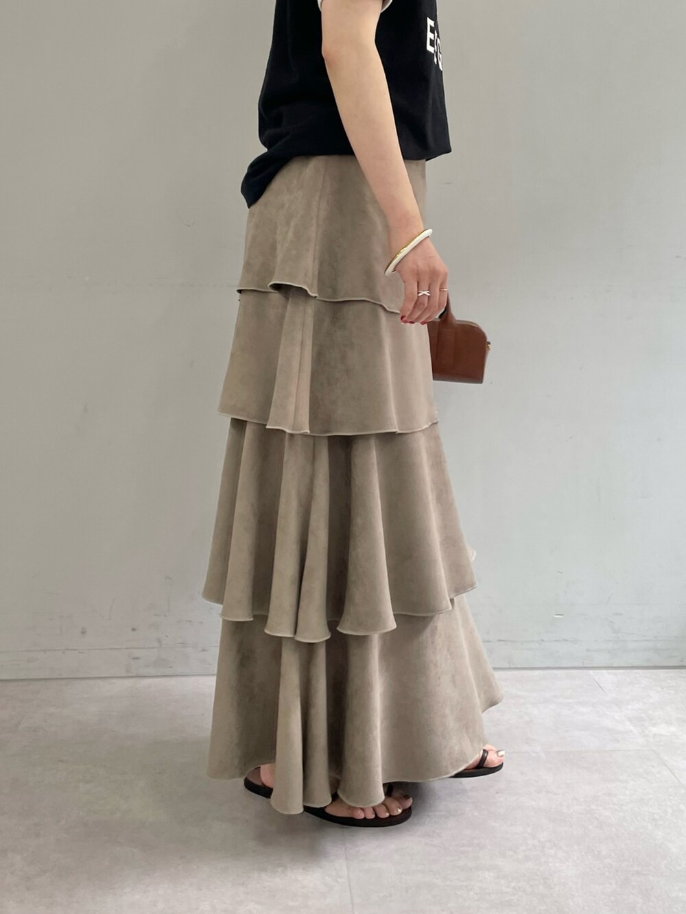 ブラック系のTシャツ/カットソー、ベージュ系のスカート、ゴールド系のブレスレットを着用したレディースの夏コーディネートの5枚目の写真