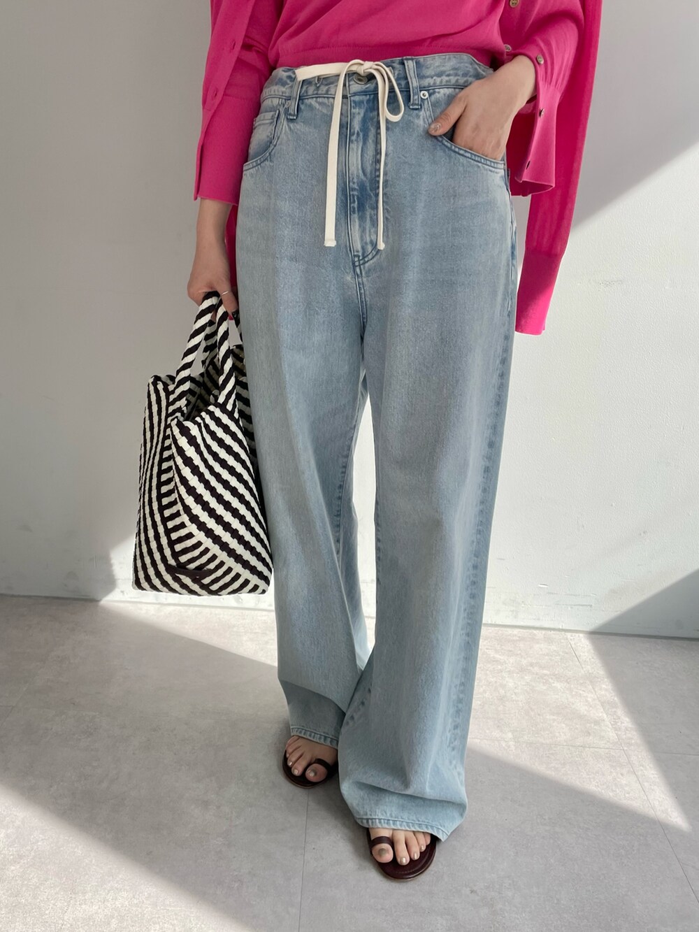 ブルー系のデニムパンツ、ブラック系のトートバッグ、ピンク系のニット/セーターを着用したレディースの春コーディネートの4枚目の写真