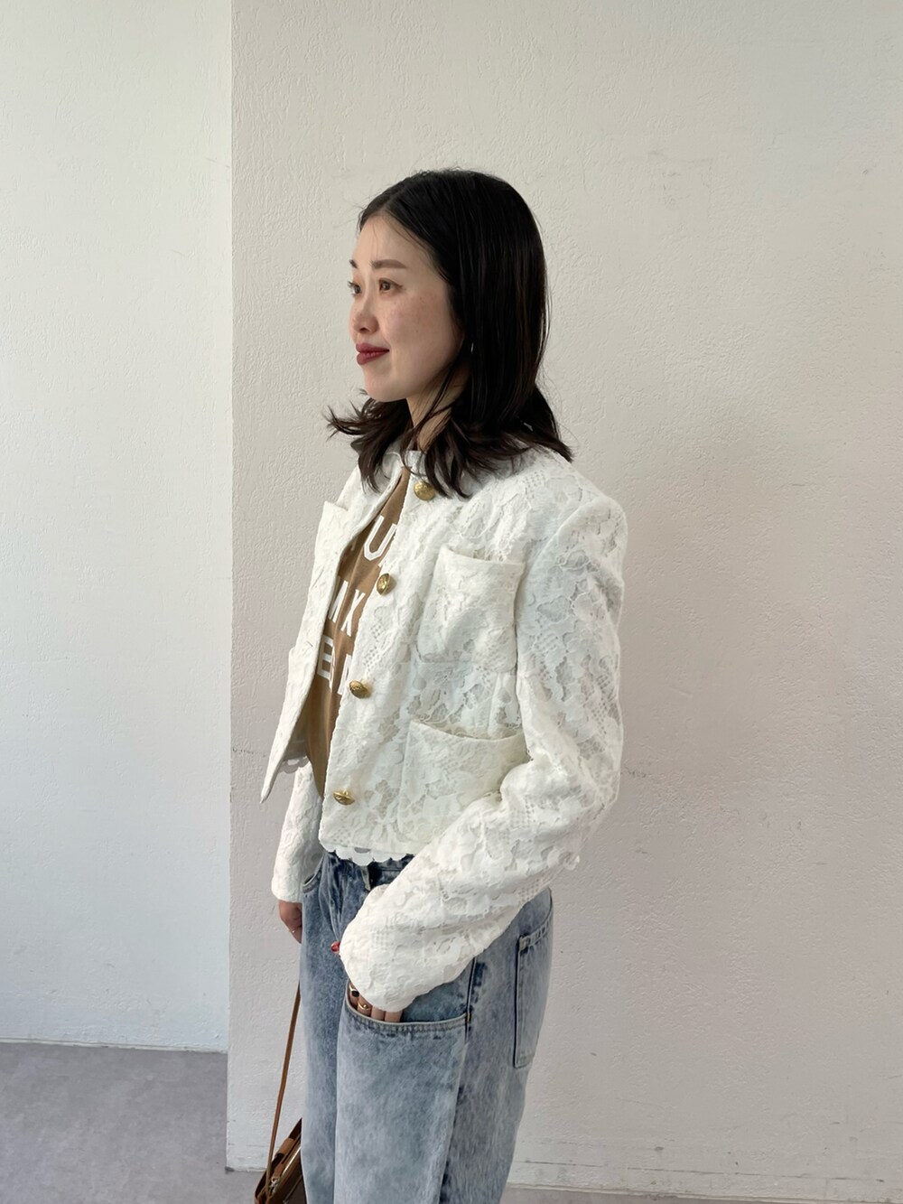 ブルー系のデニムパンツ、ブラック系のパンプス、ホワイト系のノーカラージャケットを着用したレディースの夏コーディネートの3枚目の写真