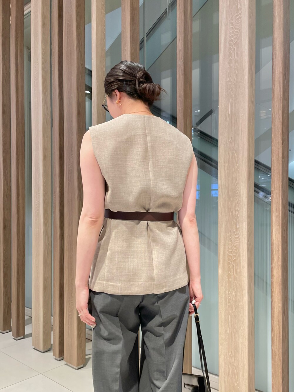 ベージュ系のベスト、ブラック系のショルダーバッグ、グレー系のスラックスを着用したレディースの春コーディネートの4枚目の写真