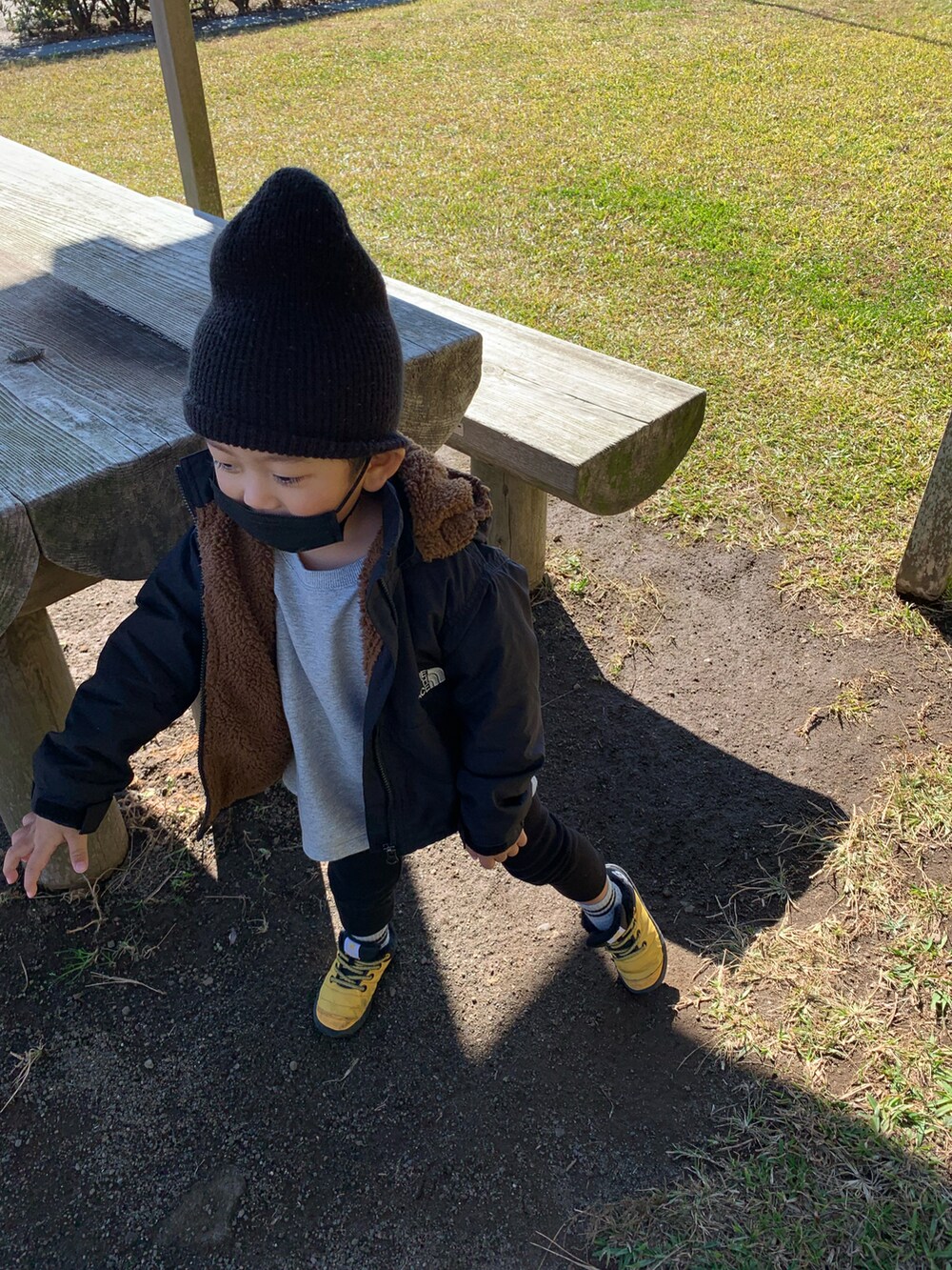 イエロー系のスニーカー、グレー系のTシャツ/カットソー、ブラック系のナイロンジャケットを着用したキッズの秋コーディネートの2枚目の写真