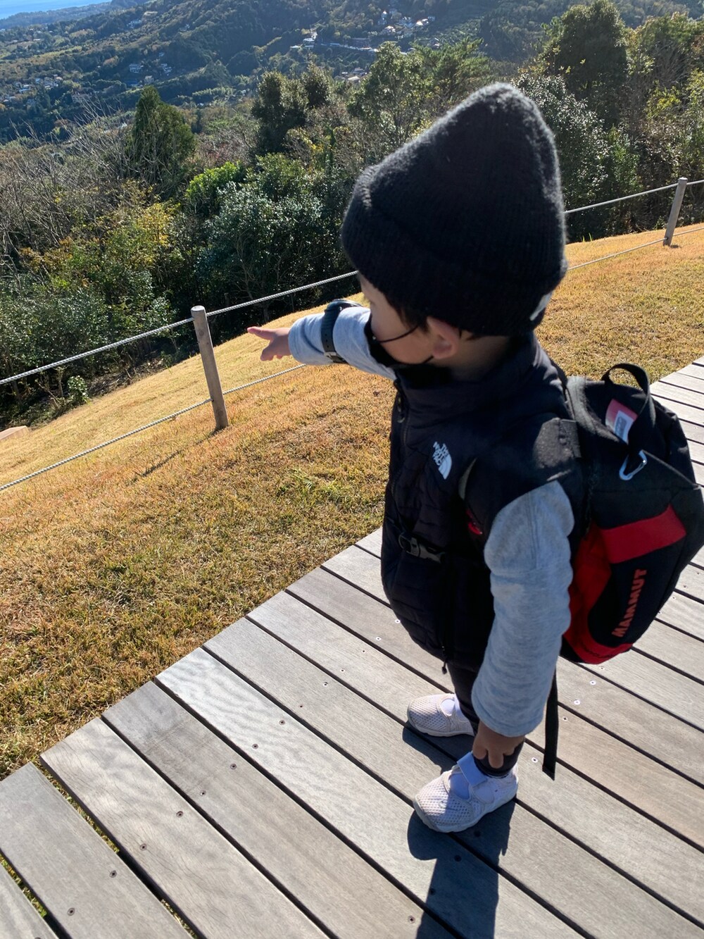 ブラック系のバックパック/リュック、ブラック系のダウンベスト、ホワイト系のスニーカーを着用したキッズの秋コーディネートの3枚目の写真