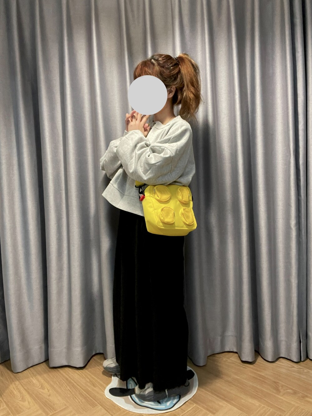 ブラック系のチノパンツ、イエロー系のバッグ、グレー系のトップスを着用したレディースの冬コーディネートの2枚目の写真