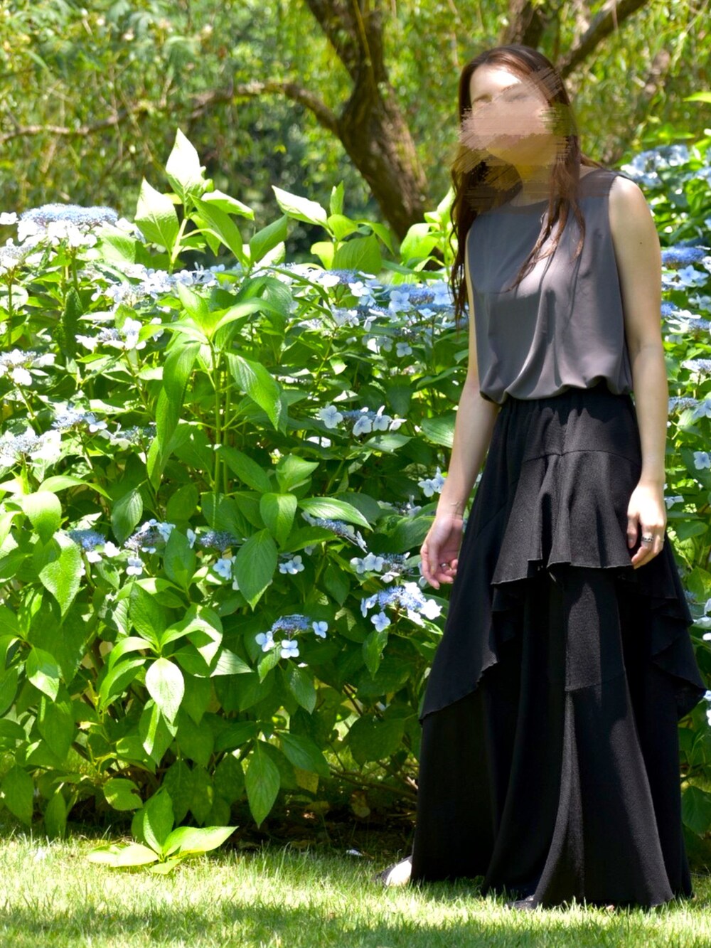 グレー系のトップス、ブラック系のスカート、ブラック系のパンプスを着用したレディースの夏コーディネートの5枚目の写真