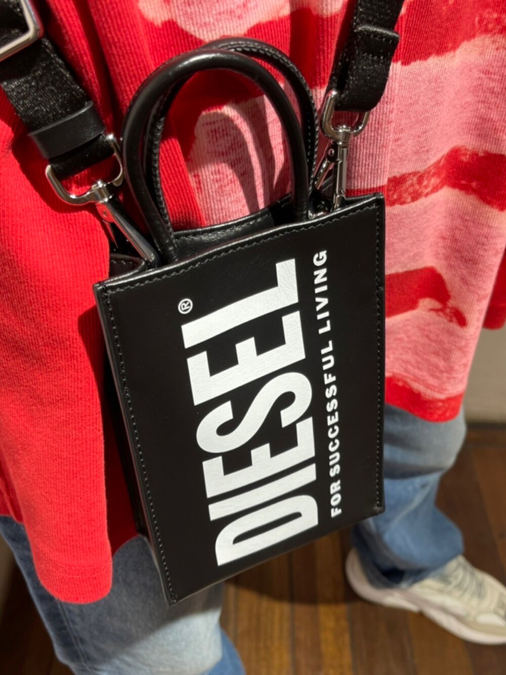 レッド系のトップス、ブルー系のデニムパンツ、ホワイト系のスニーカーを着用したレディースの夏コーディネートの2枚目の写真