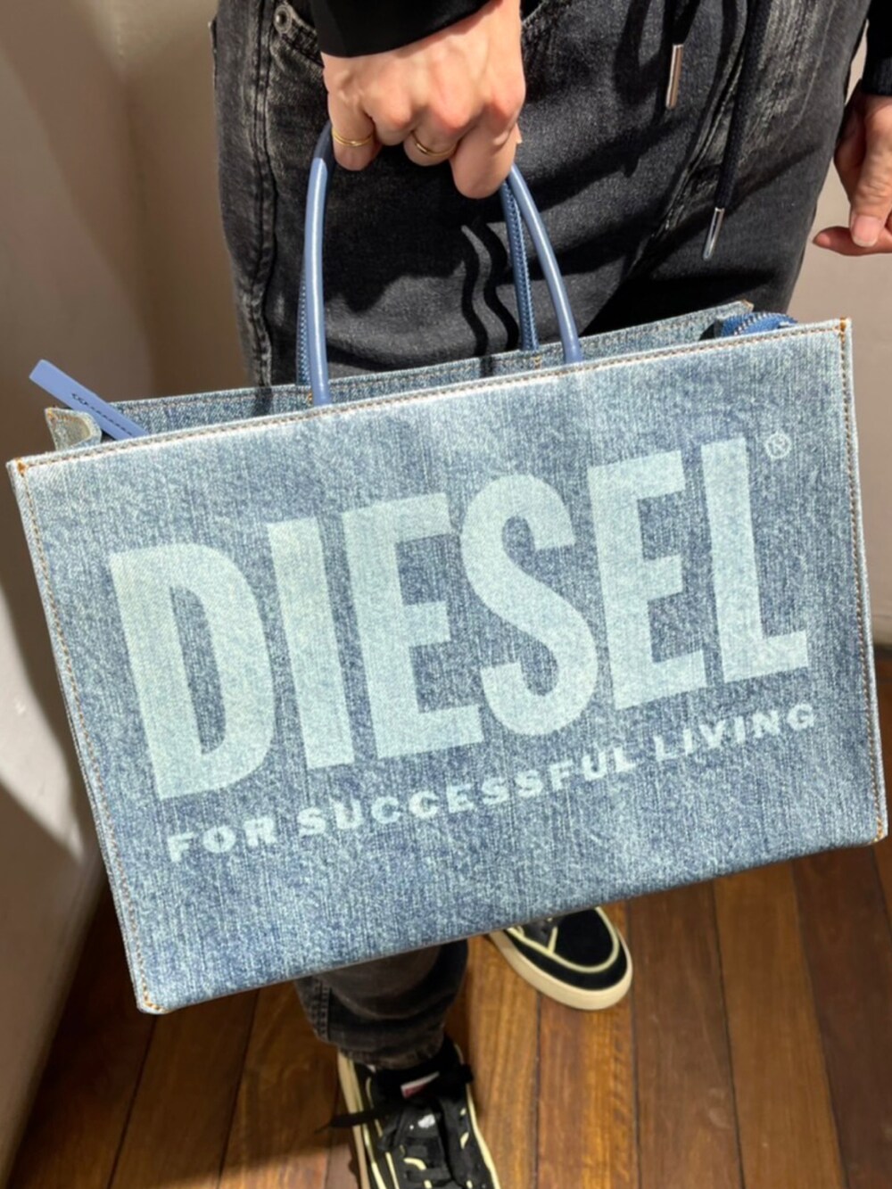 ブルー系のバッグ、ブラック系のデニムパンツ、ブラック系のスニーカーを着用したレディースの夏コーディネートの2枚目の写真