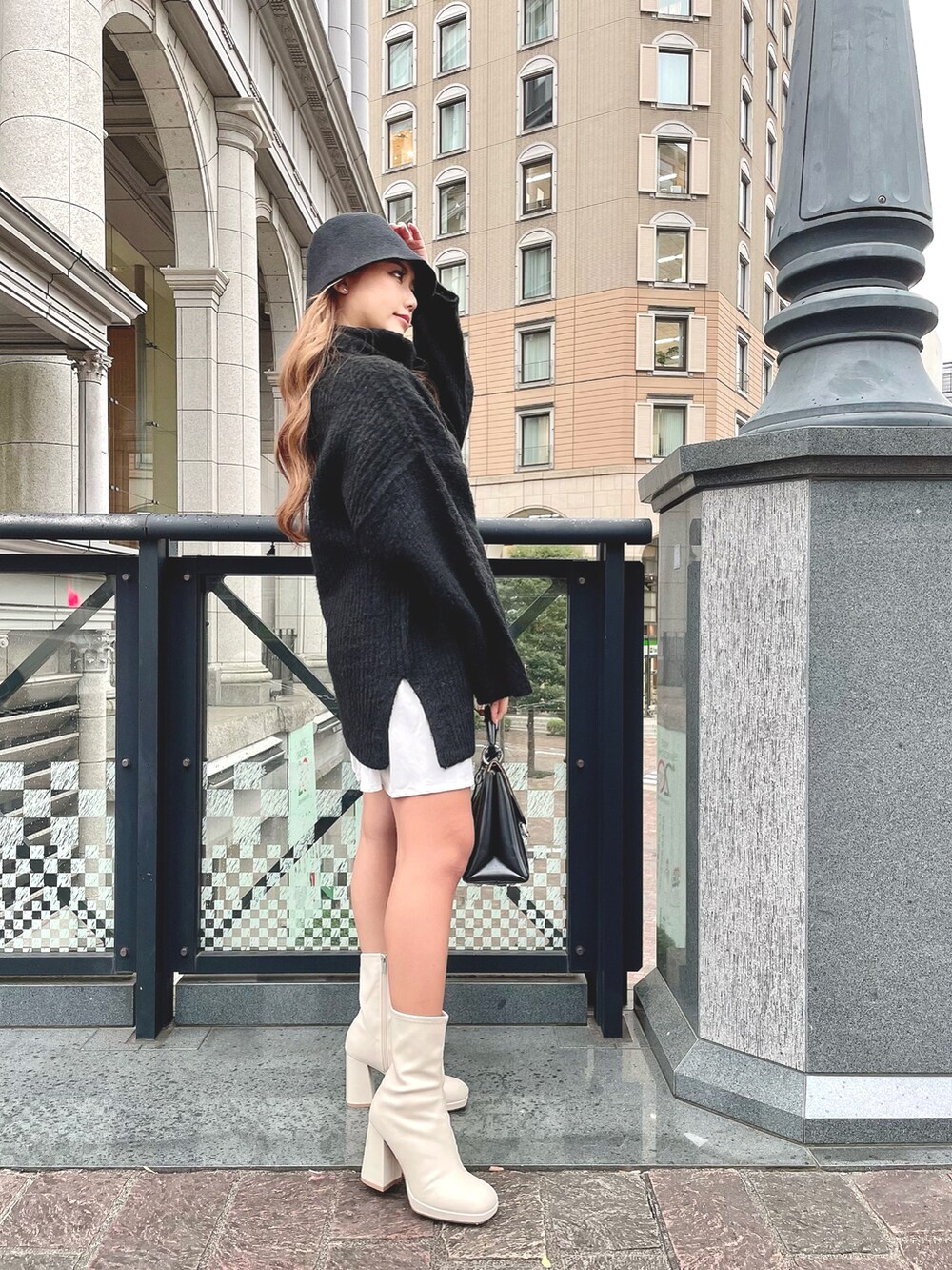 ブラック系のニット/セーター、ホワイト系のワンピース、ブラック系のバッグを着用したレディースの秋コーディネートの2枚目の写真