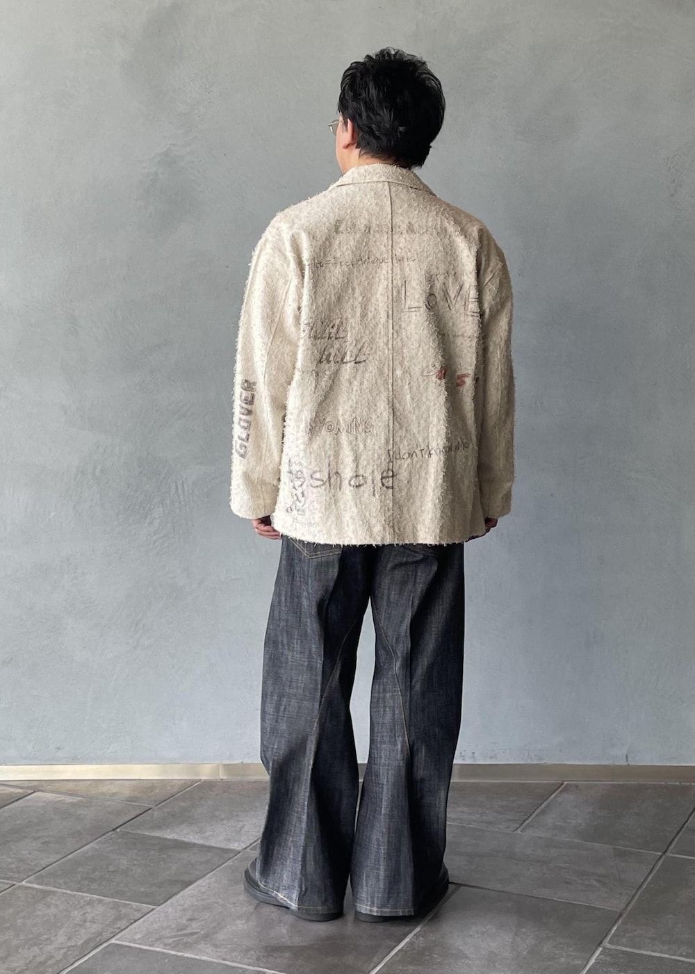 ブラック系のスリッポン、ブラック系のスウェット、ホワイト系のテーラードジャケットを着用したメンズの冬コーディネートの3枚目の写真