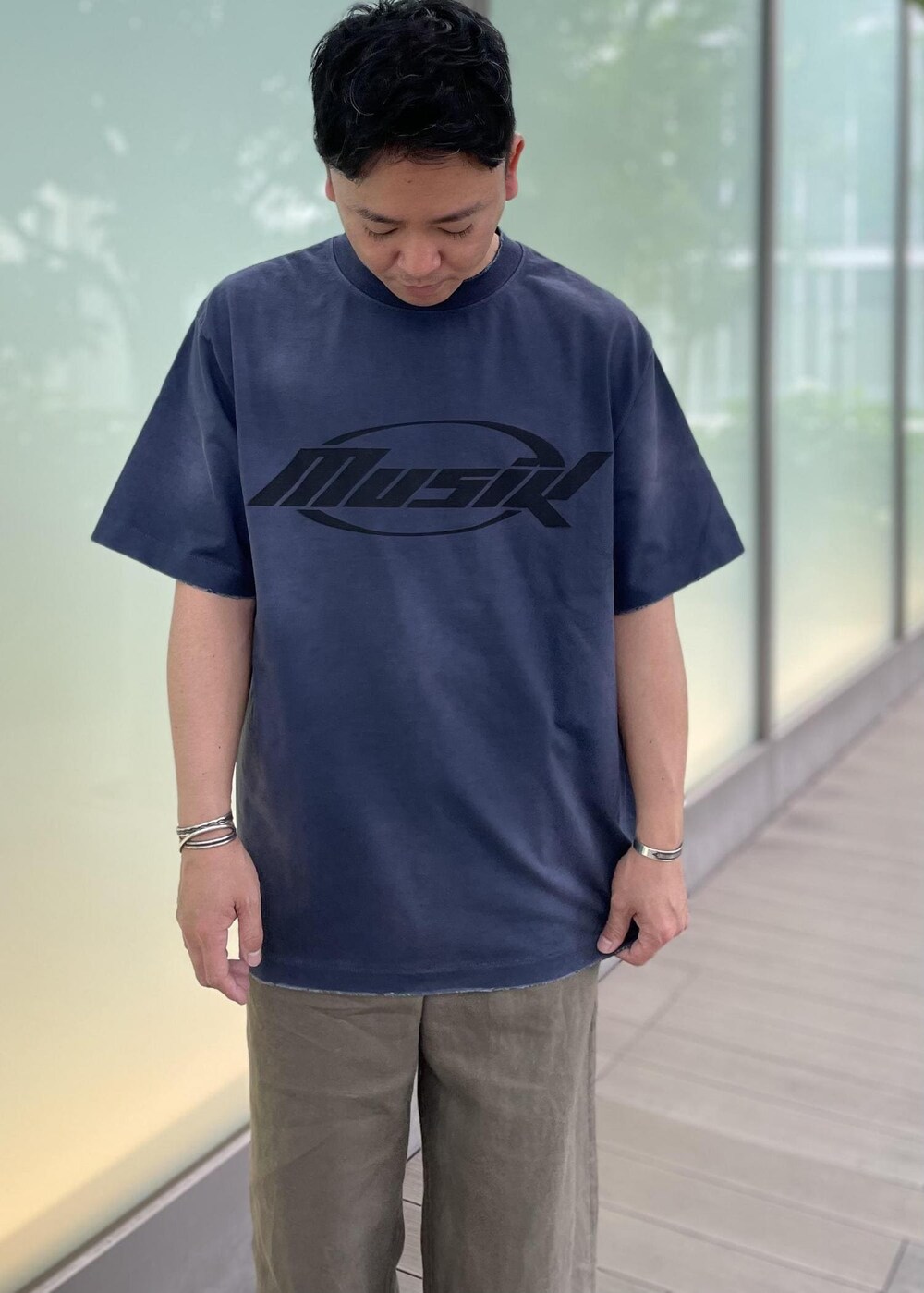 グリーン系のスラックス、ブラック系のサンダルを着用したメンズの春コーディネートの2枚目の写真