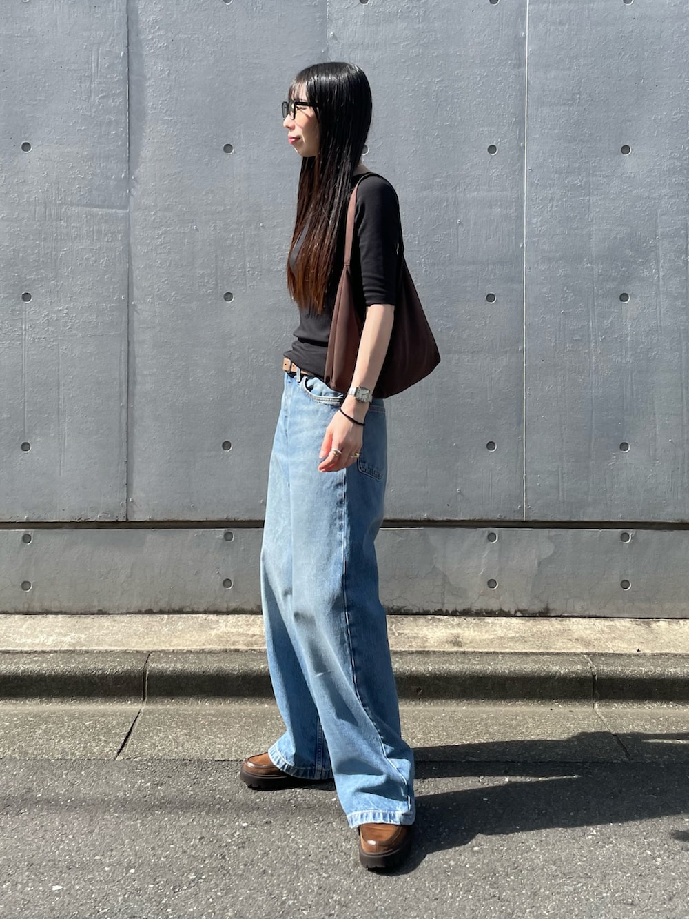 ブラック系のTシャツ/カットソー、ブルー系のデニムパンツ、ブラウン系のショルダーバッグを着用したレディースの夏コーディネートの2枚目の写真
