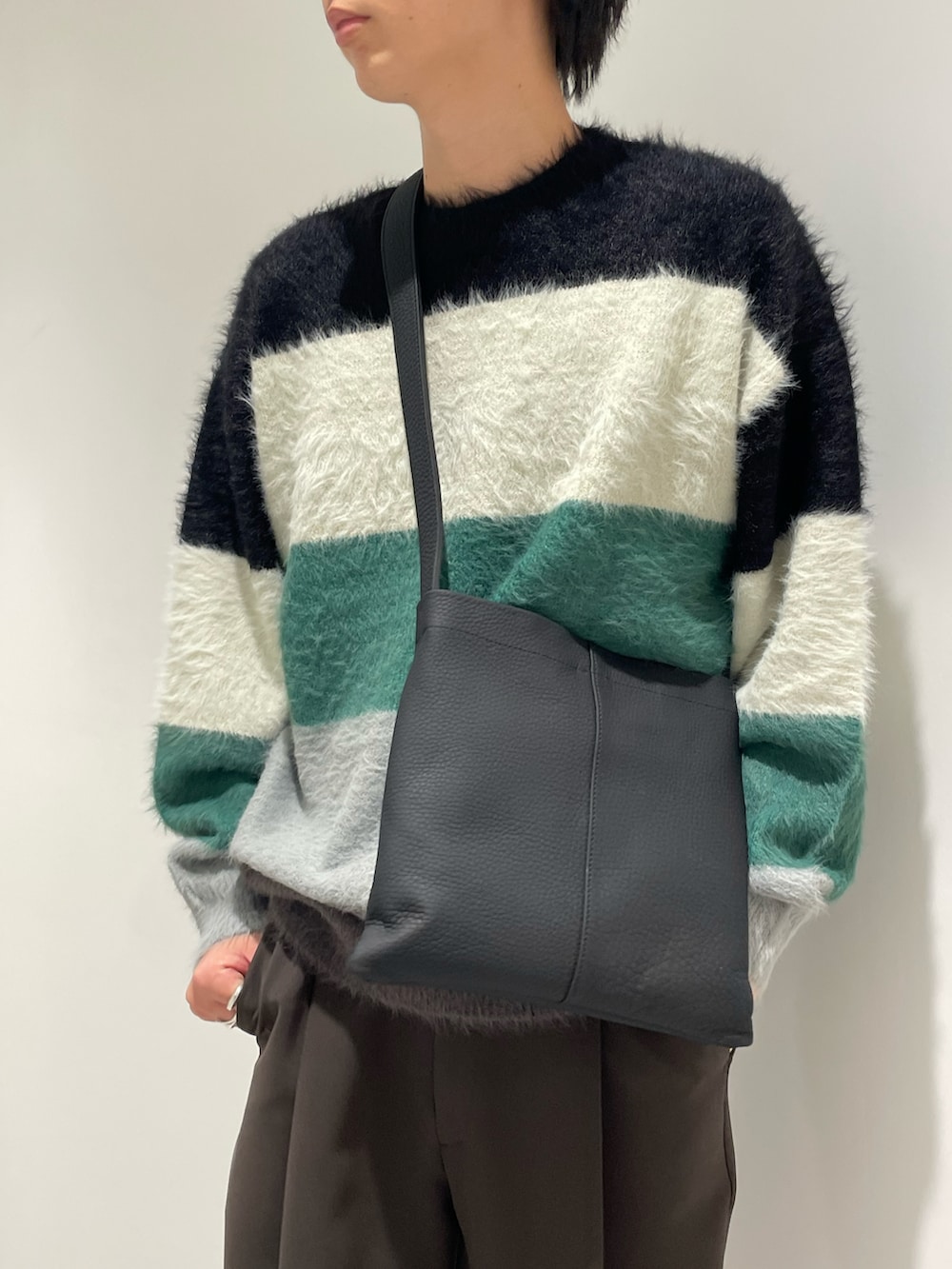 ブラック系のニット/セーター、ブラック系のトートバッグ、シルバー系のジャケット/アウターを着用したメンズの秋コーディネートの5枚目の写真