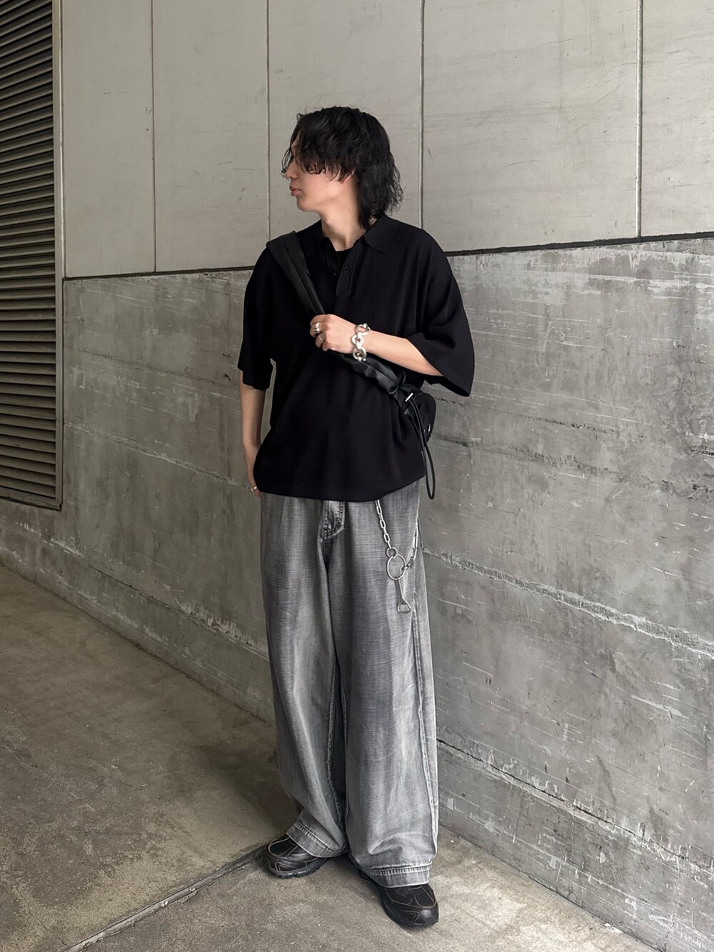 ブラック系のポロシャツ、ブラック系のショルダーバッグ、グレー系のデニムパンツを着用したメンズの夏コーディネートの3枚目の写真