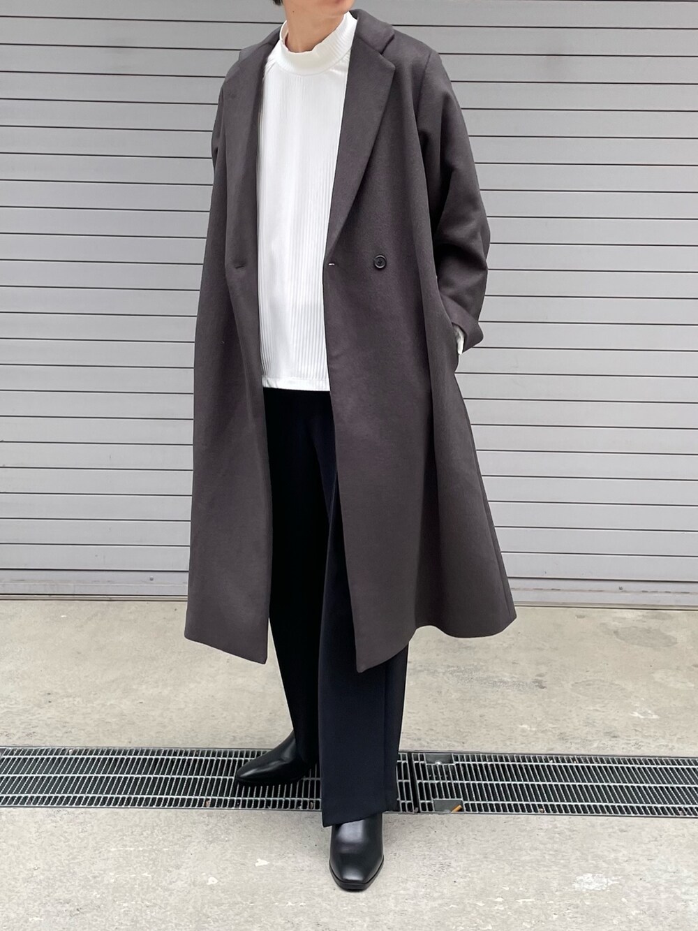 グレー系のチェスターコート、ホワイト系のTシャツ/カットソー、ブラック系のその他パンツを着用したメンズの冬コーディネートの2枚目の写真