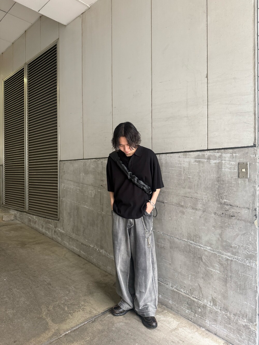 ブラック系のポロシャツ、ブラック系のショルダーバッグ、グレー系のデニムパンツを着用したメンズの夏コーディネートの2枚目の写真