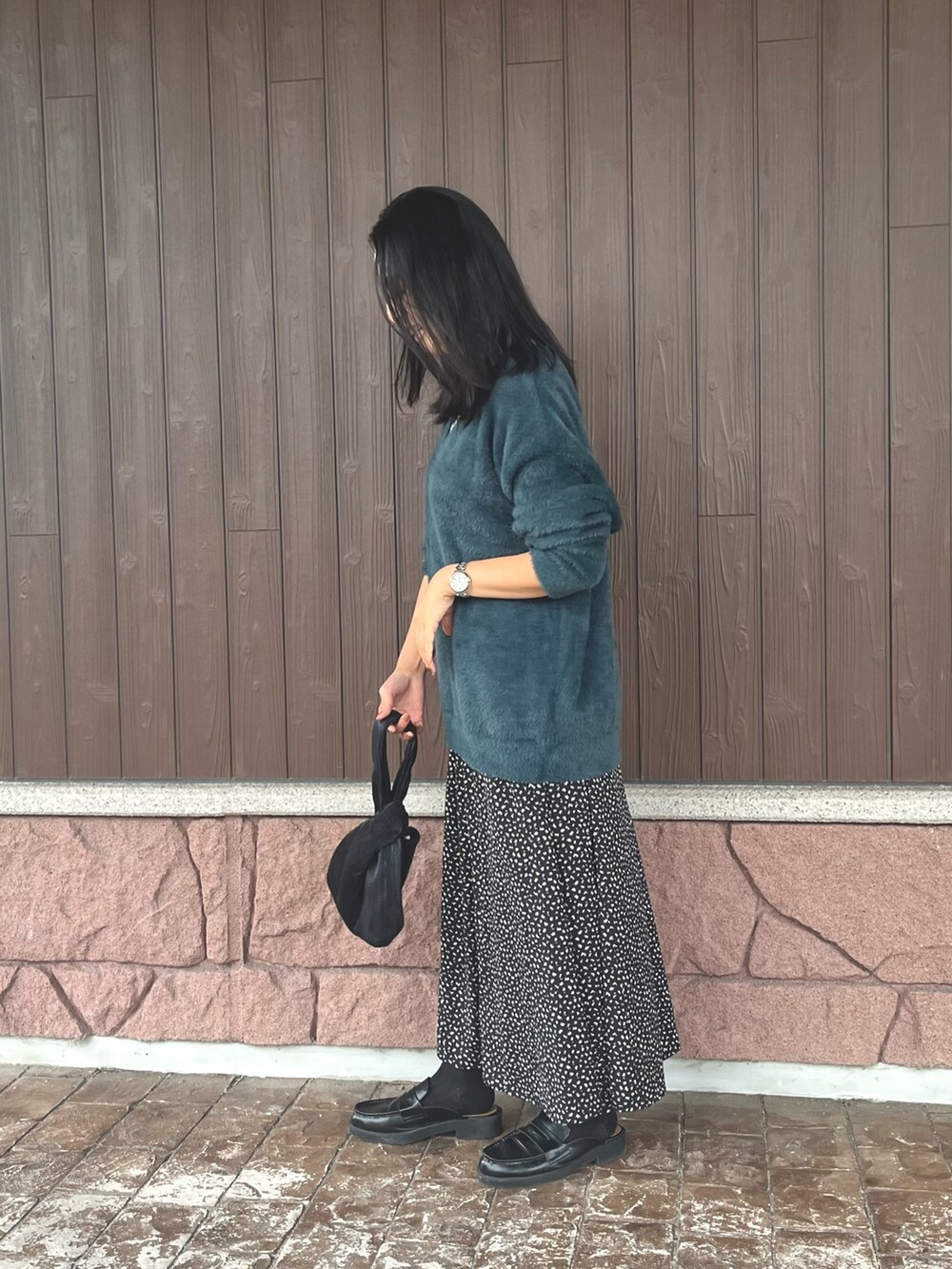 グレー系のタンクトップ、グリーン系のニット/セーター、ブラック系のスカートを着用したレディースの秋コーディネートの3枚目の写真