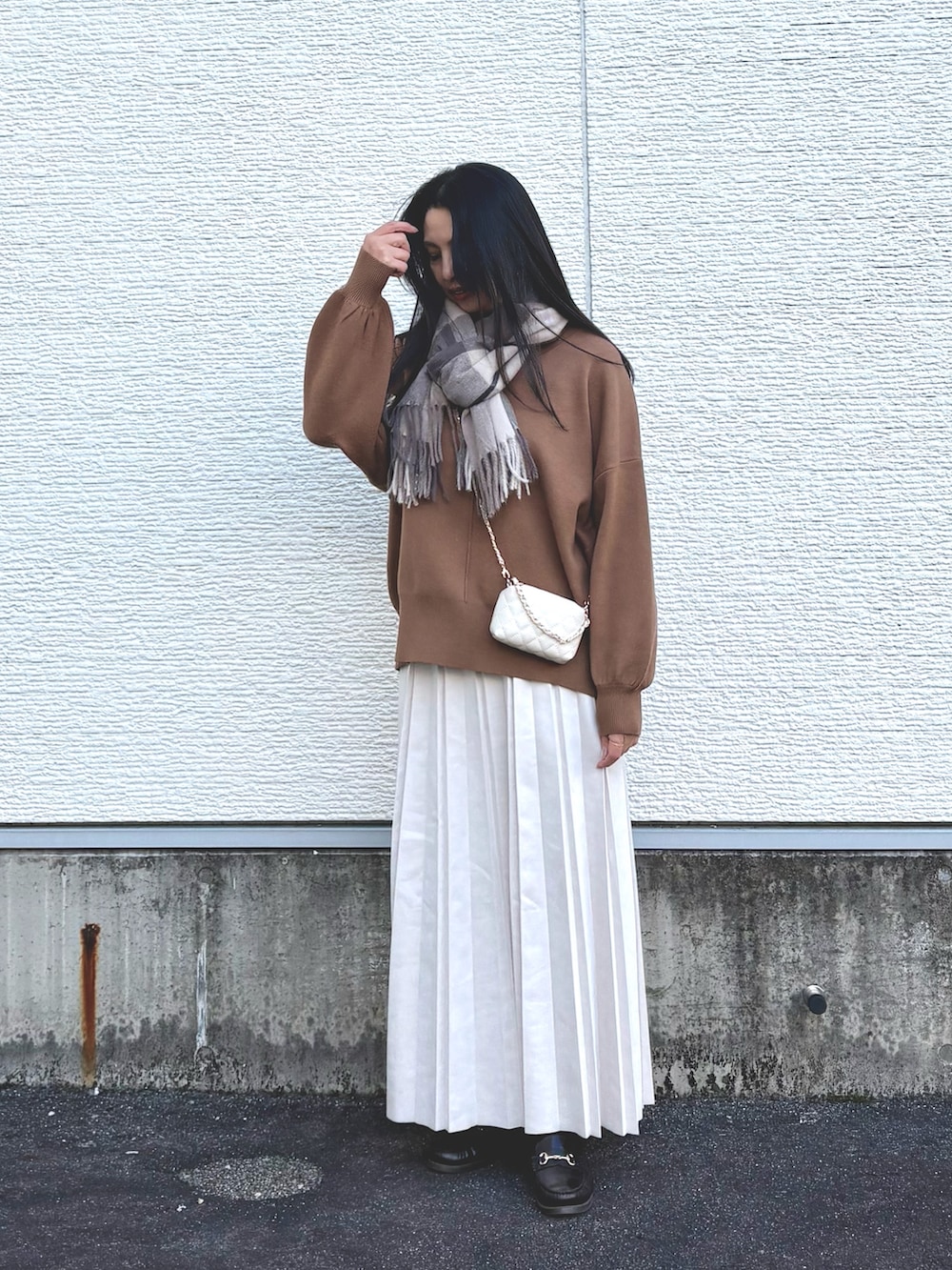 イエロー系のニット/セーター、ホワイト系のショルダーバッグ、ベージュ系のスカートを着用したレディースの冬コーディネートの4枚目の写真