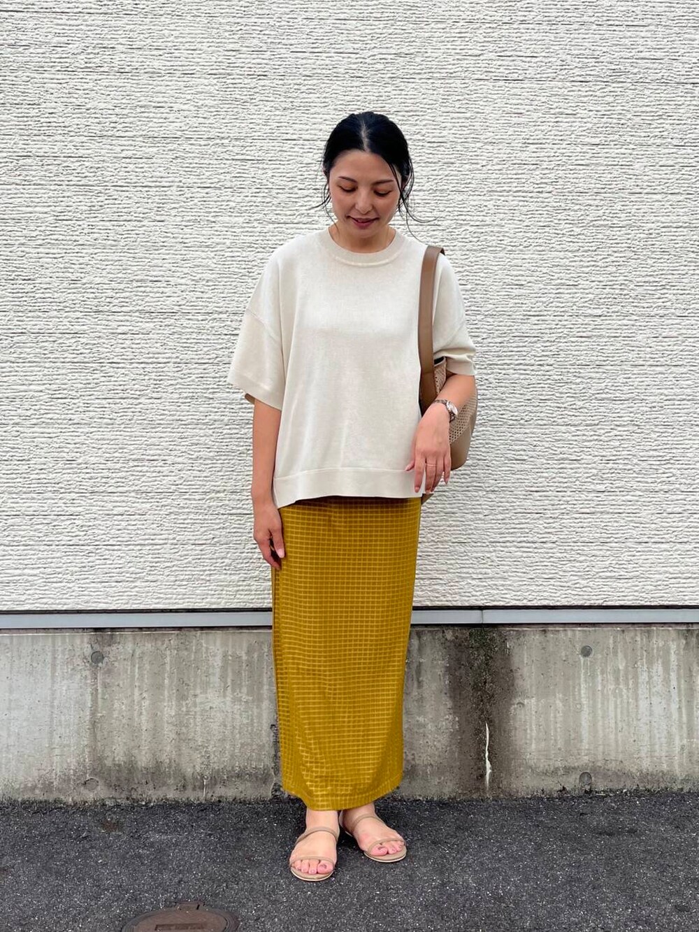 ベージュ系のショルダーバッグ、ホワイト系のニット/セーター、イエロー系のスカートを着用したレディースの夏コーディネートの3枚目の写真