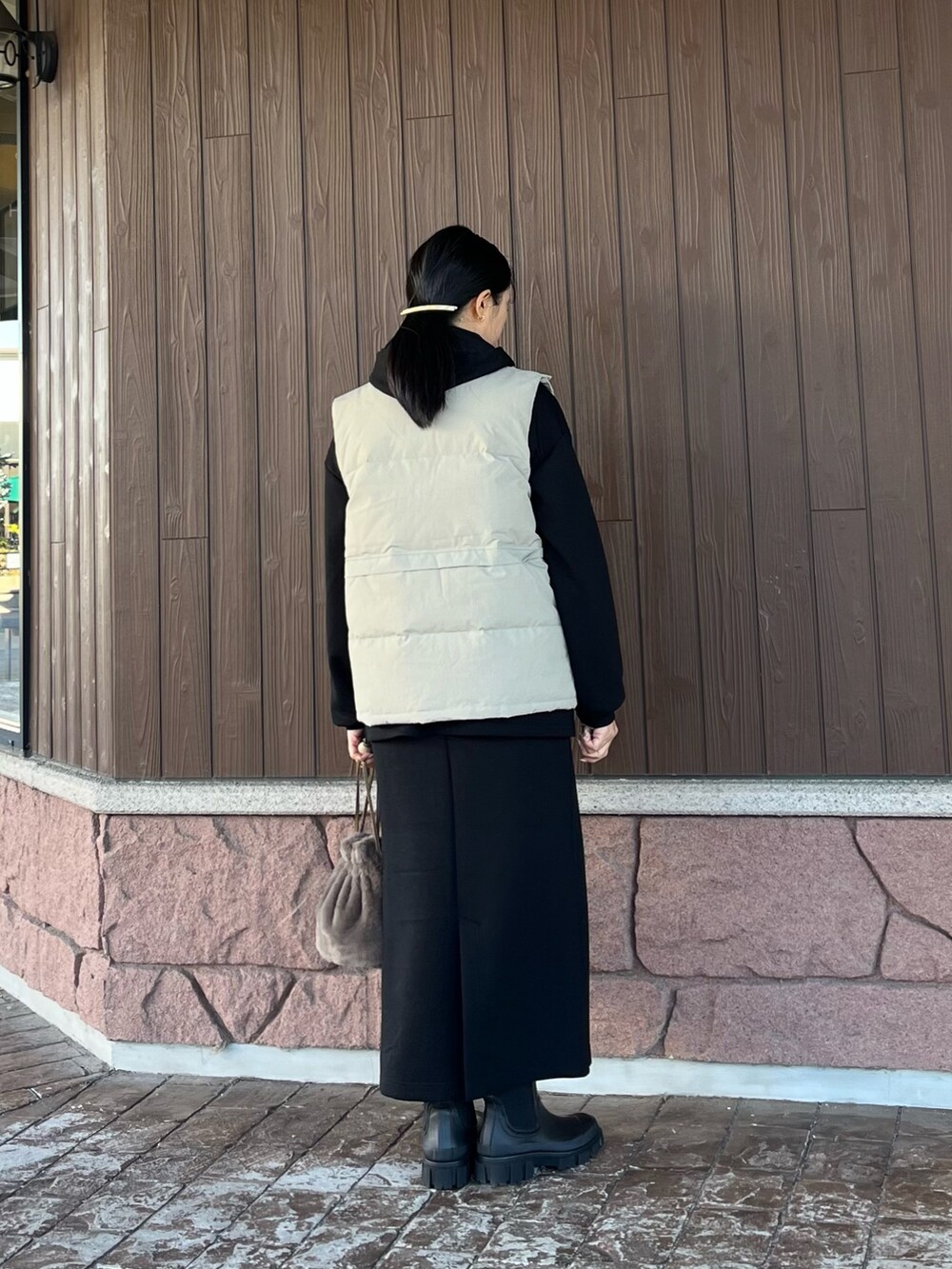 ブラック系のワンピース、ベージュ系のダウンベスト、ブラウン系のスカートを着用したレディースの冬コーディネートの2枚目の写真