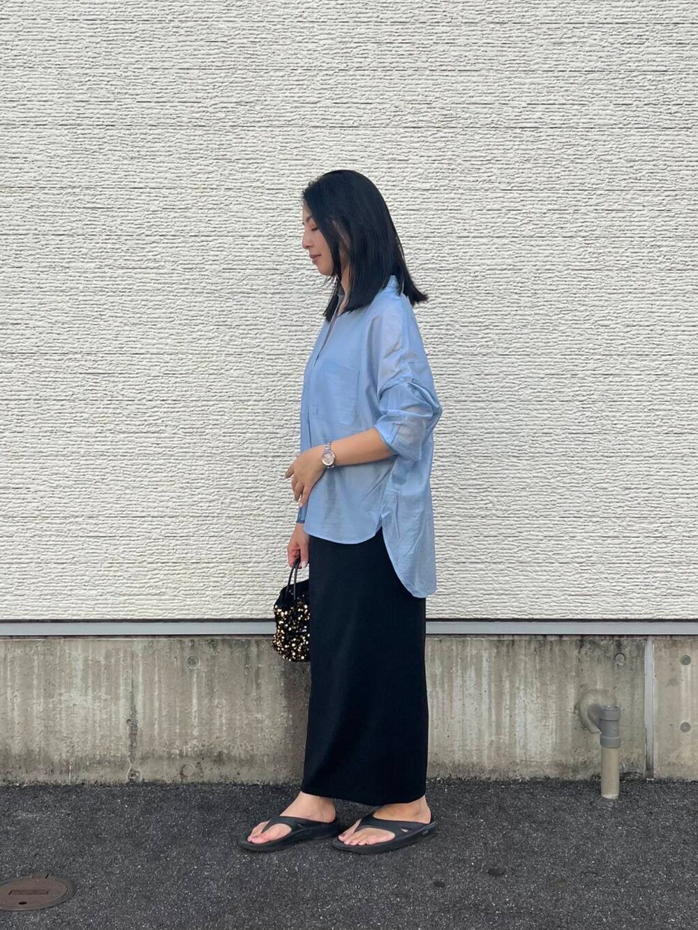 ゴールド系のショルダーバッグ、ブルー系のシャツ/ブラウス、ブラック系のスカートを着用したレディースの夏コーディネートの2枚目の写真