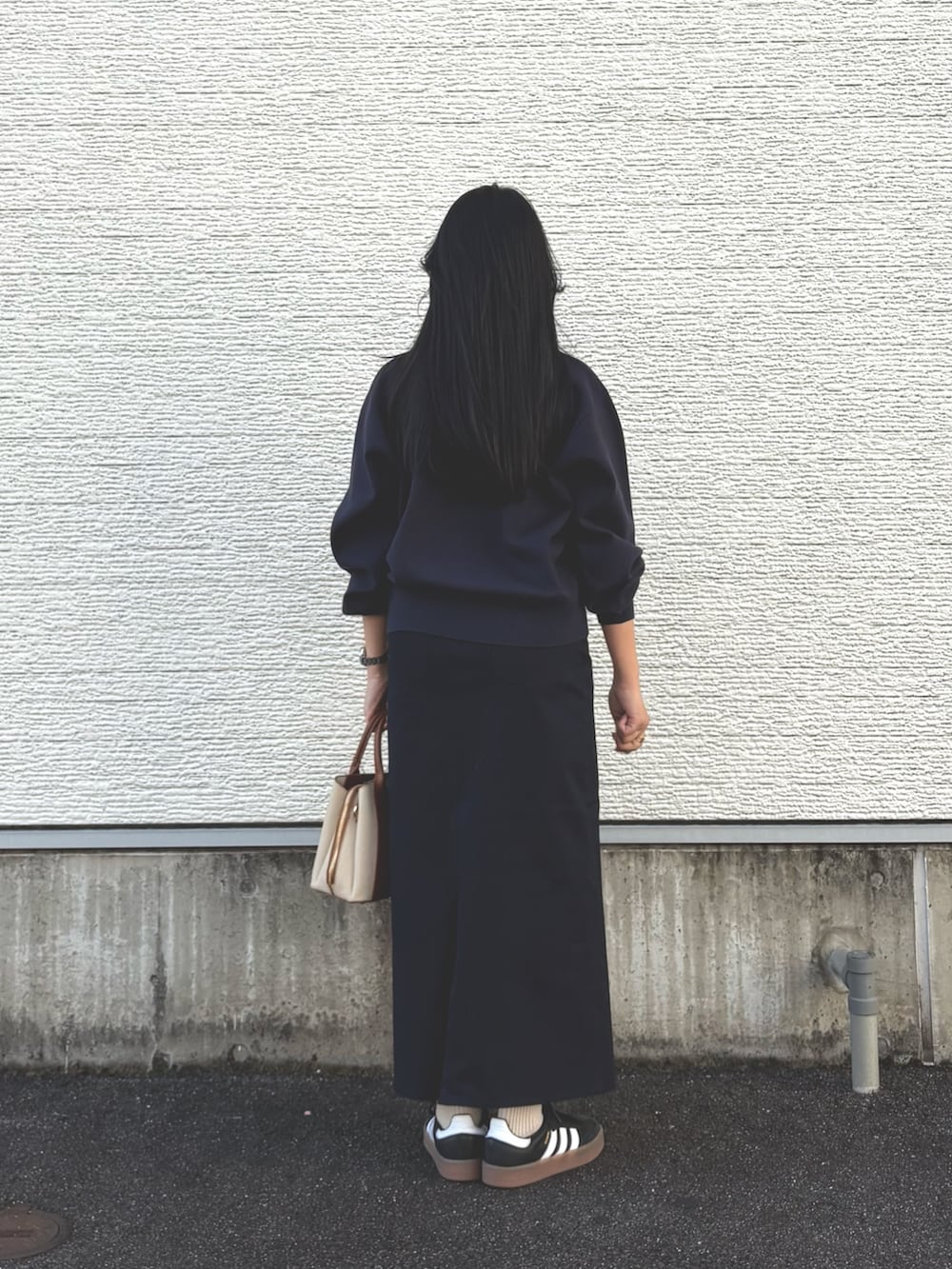 ブルー系のニット/セーター、ブルー系のスカート、ホワイト系のハンドバッグを着用したレディースの冬コーディネートの4枚目の写真