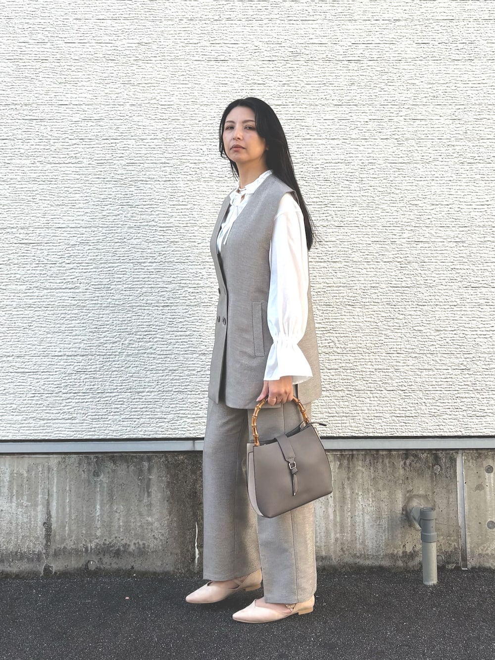 その他のハンドバッグ、ホワイト系のパンプス、ベージュ系のセットアップを着用したレディースの冬コーディネートの5枚目の写真