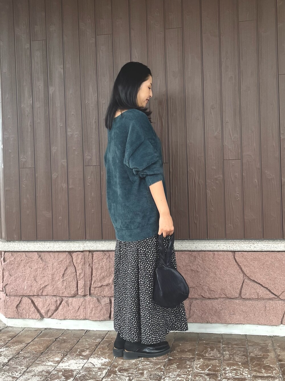 グレー系のタンクトップ、グリーン系のニット/セーター、ブラック系のスカートを着用したレディースの秋コーディネートの2枚目の写真