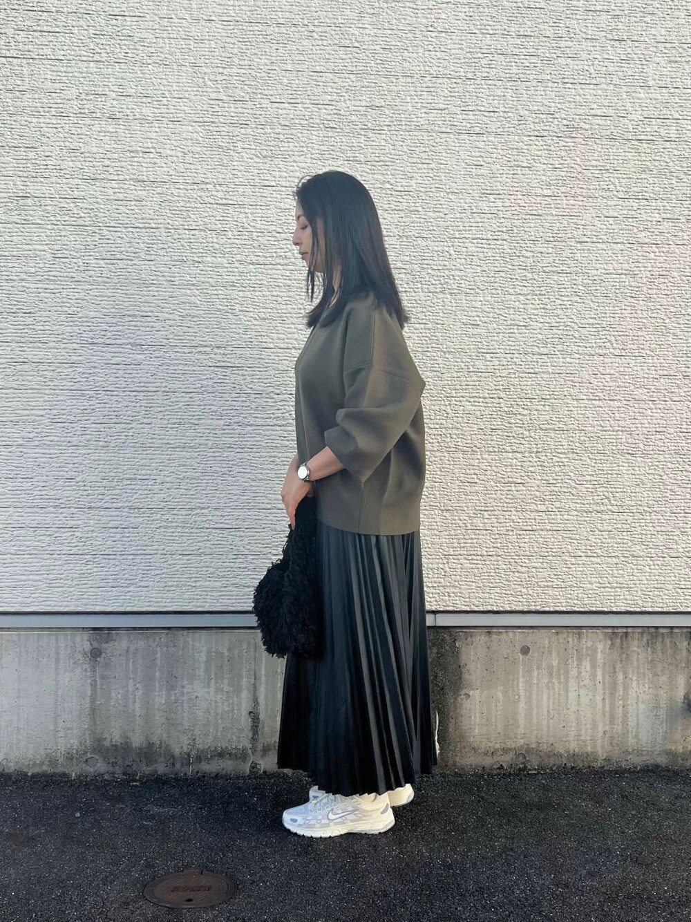 ブラック系のショルダーバッグ、グリーン系のニット/セーター、ホワイト系のスニーカーを着用したレディースの秋コーディネートの3枚目の写真