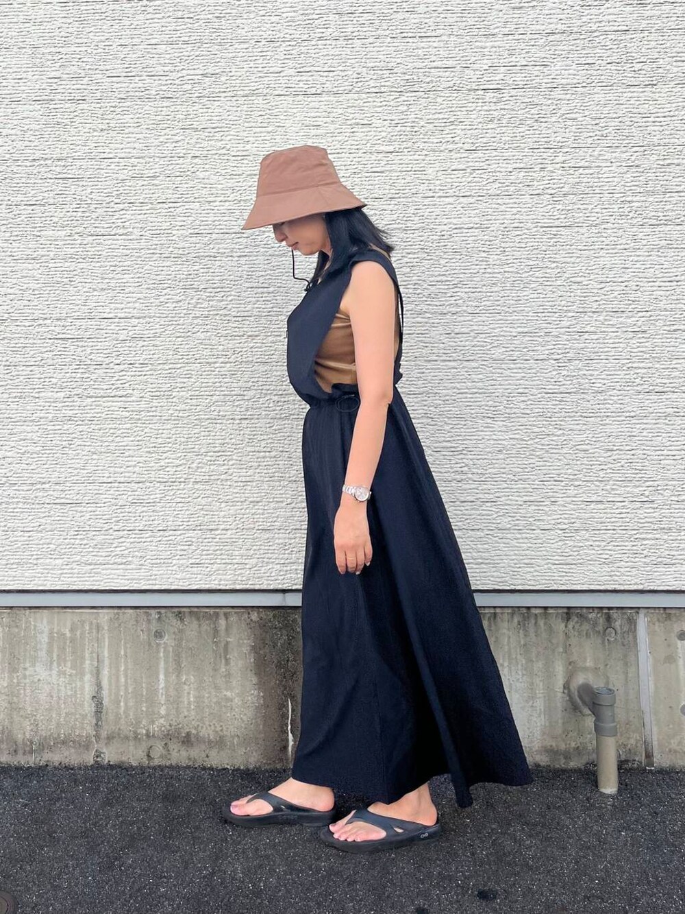 ゴールド系のショルダーバッグ、ブラック系のワンピース、ベージュ系のタンクトップを着用したレディースの夏コーディネートの2枚目の写真