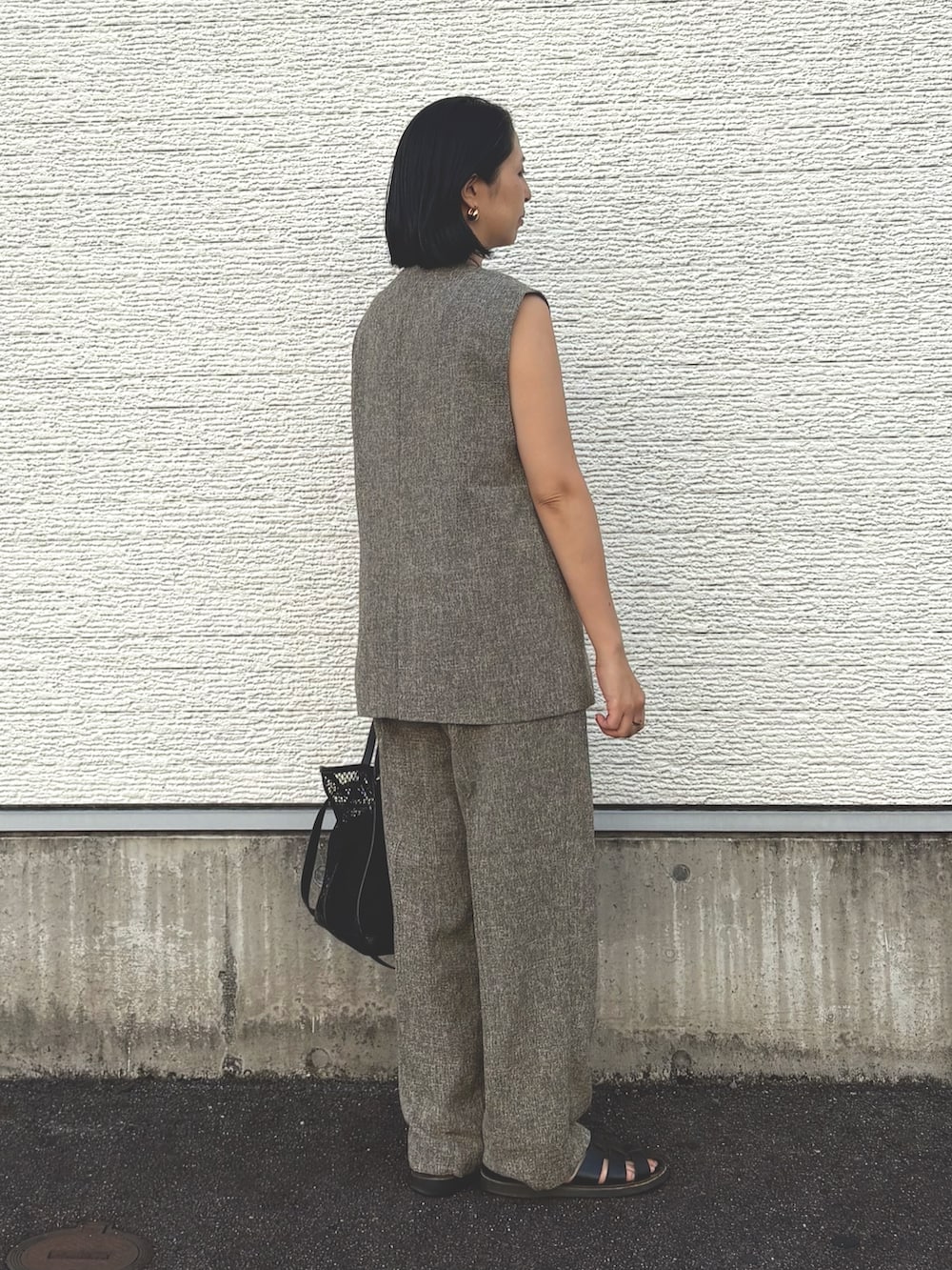 ベージュ系のダウンベスト、ブラック系のトートバッグ、ブラック系のニット/セーターを着用したレディースの夏コーディネートの3枚目の写真