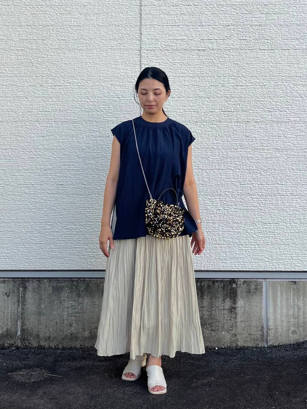 ゴールド系のショルダーバッグ、ベージュ系のスカート、ブルー系のシャツ/ブラウスを着用したレディースの夏コーディネートの3枚目の写真