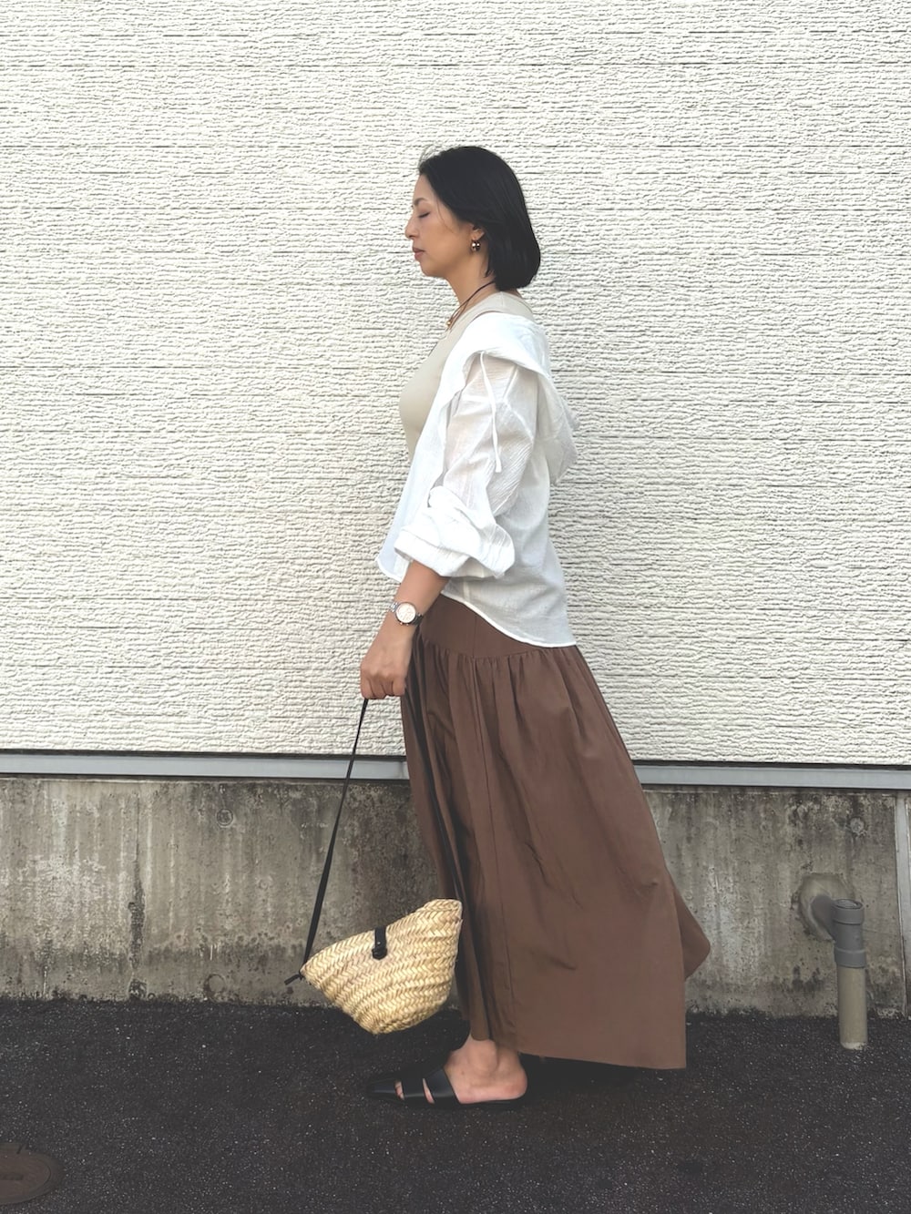 ベージュ系のワンピース、ホワイト系のシャツ/ブラウス、ブラック系のサンダルを着用したレディースの夏コーディネートの2枚目の写真