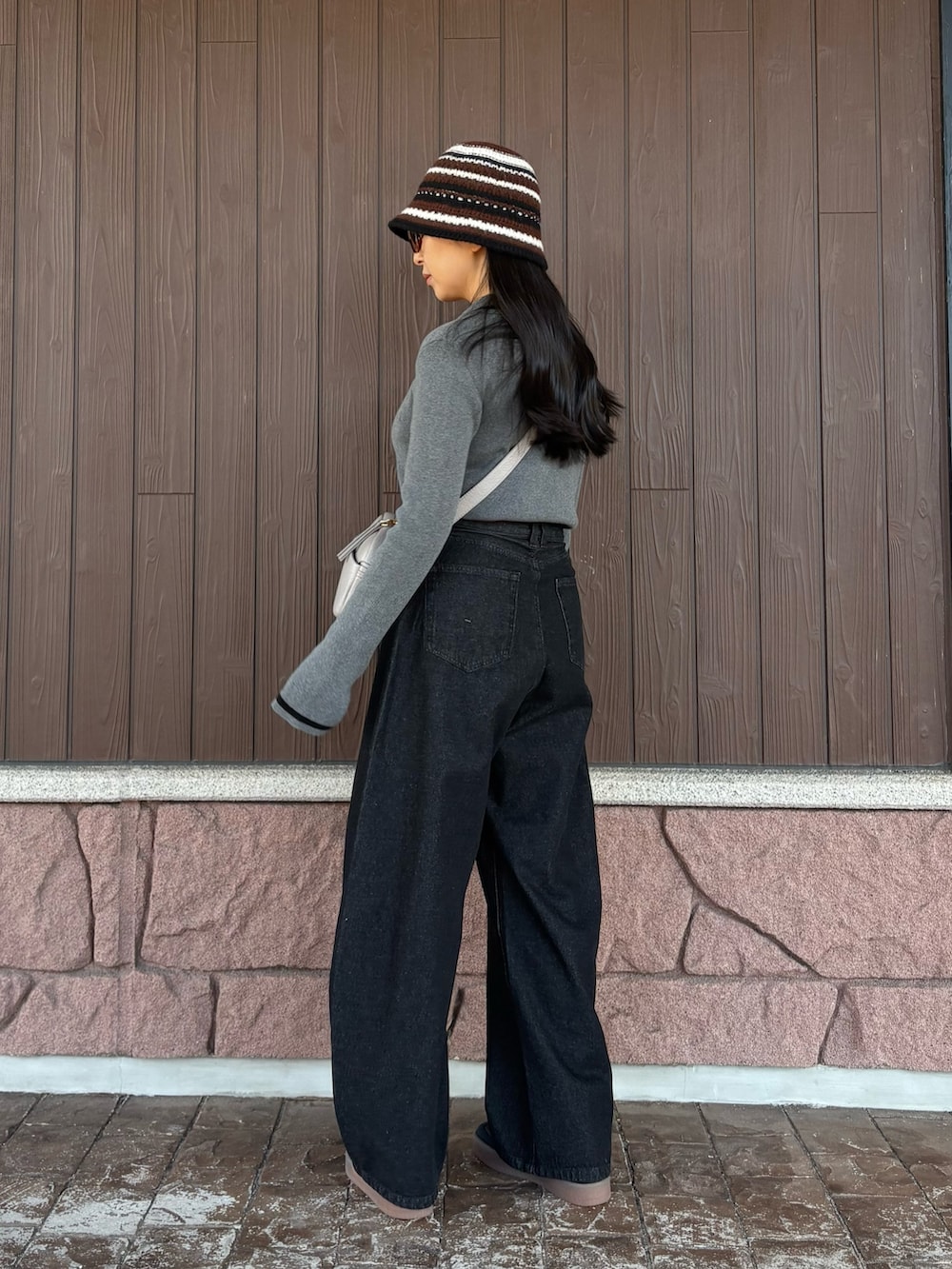 グレー系のニット/セーター、ブラック系のデニムパンツ、グレー系のショルダーバッグを着用したレディースの冬コーディネートの3枚目の写真