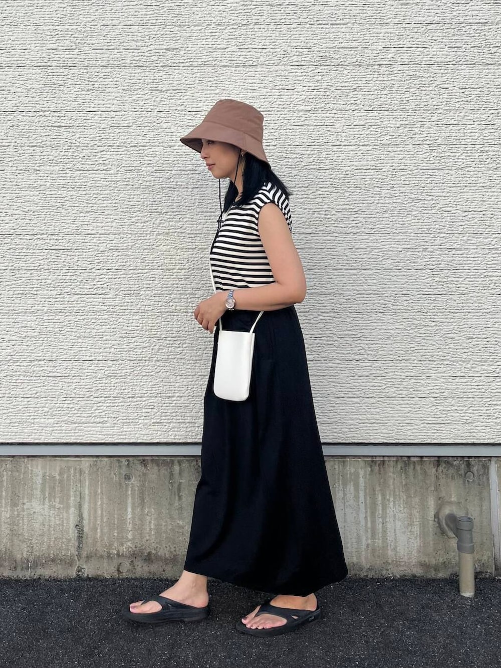 ブラック系のワンピース、ホワイト系のショルダーバッグ、ブラウン系のハットを着用したレディースの夏コーディネートの2枚目の写真