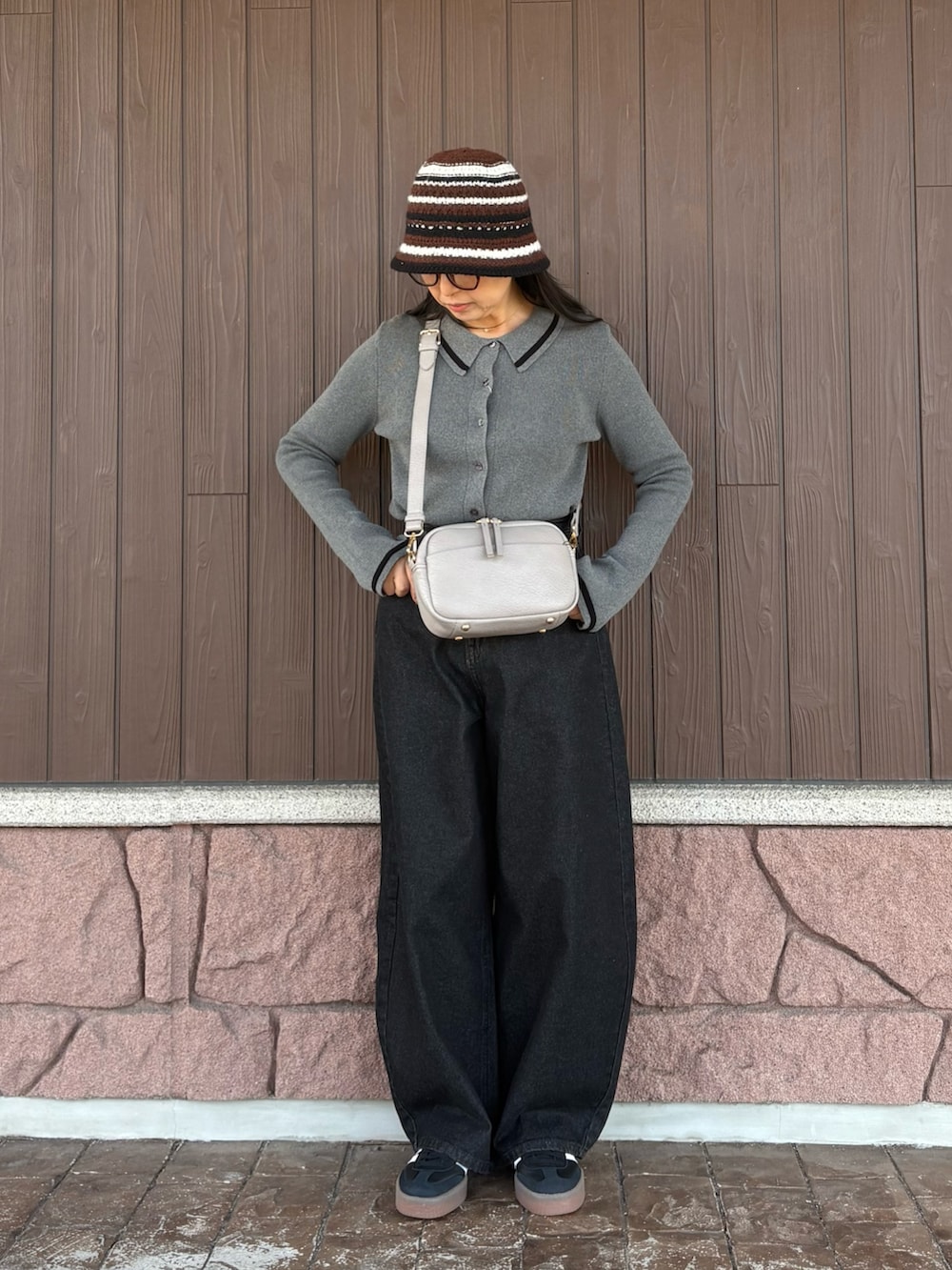 グレー系のニット/セーター、ブラック系のデニムパンツ、グレー系のショルダーバッグを着用したレディースの冬コーディネートの2枚目の写真