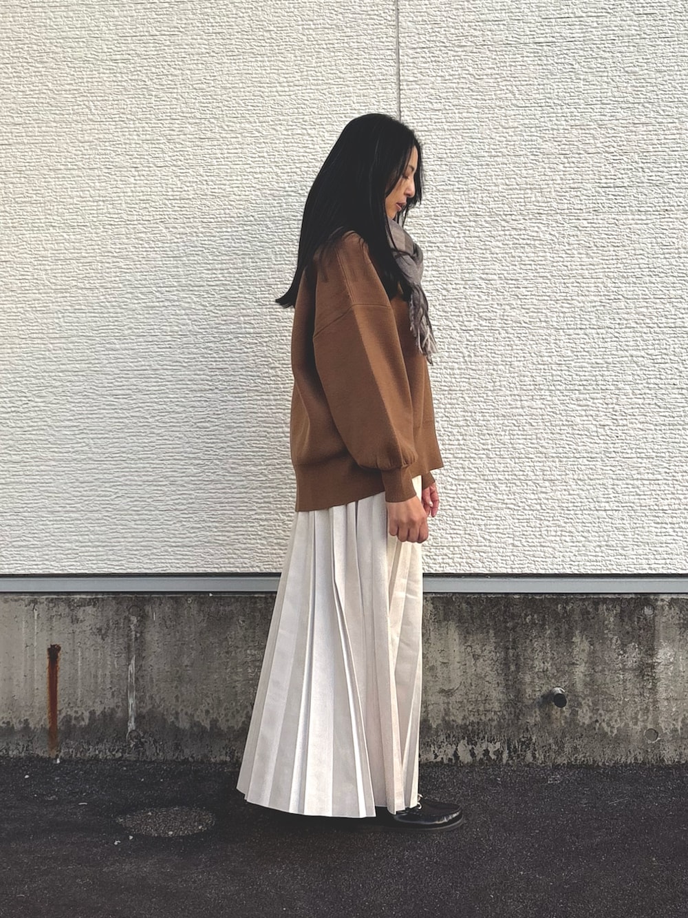 イエロー系のニット/セーター、ホワイト系のショルダーバッグ、ベージュ系のスカートを着用したレディースの冬コーディネートの2枚目の写真