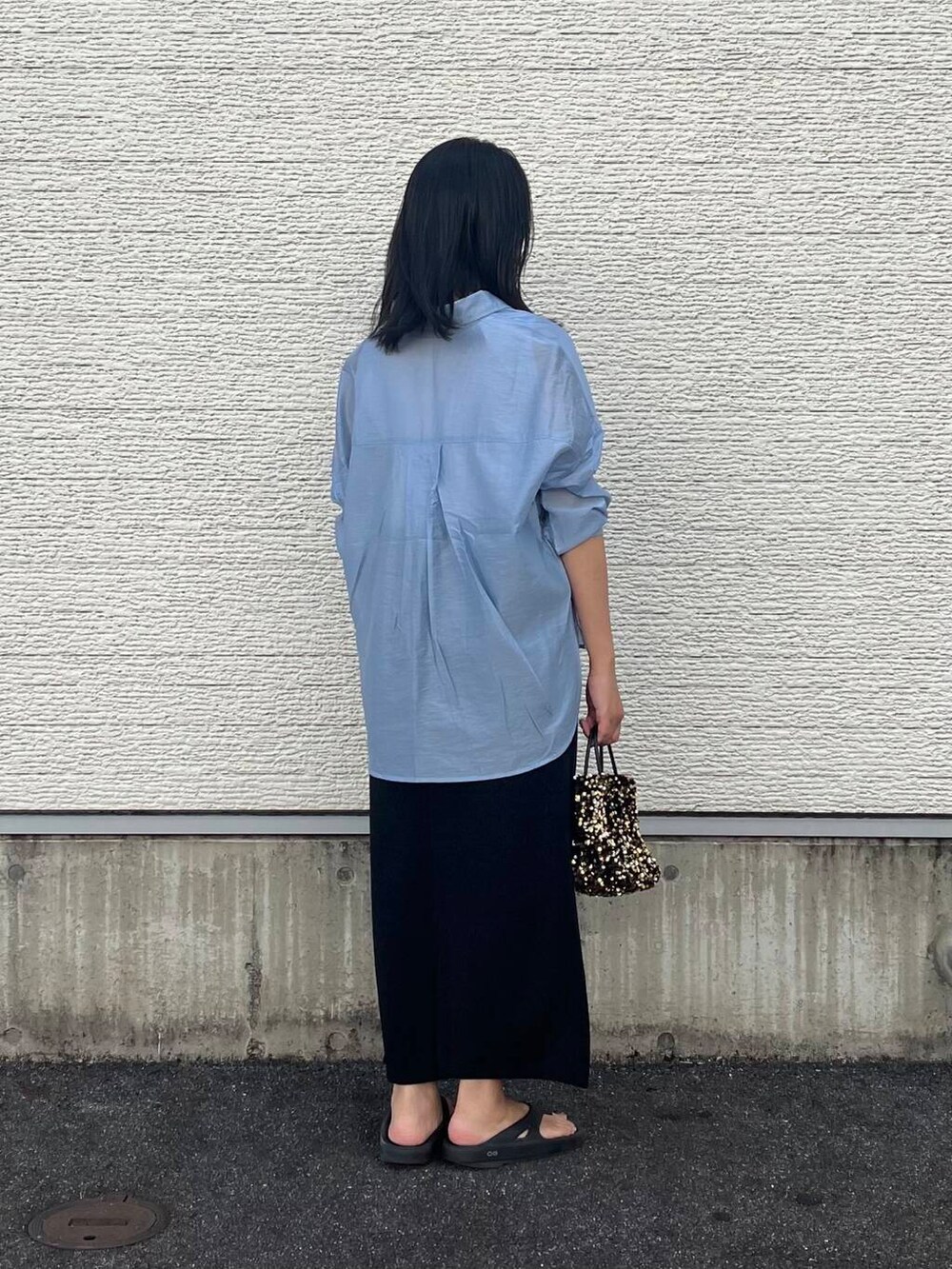 ゴールド系のショルダーバッグ、ブルー系のシャツ/ブラウス、ブラック系のスカートを着用したレディースの夏コーディネートの3枚目の写真